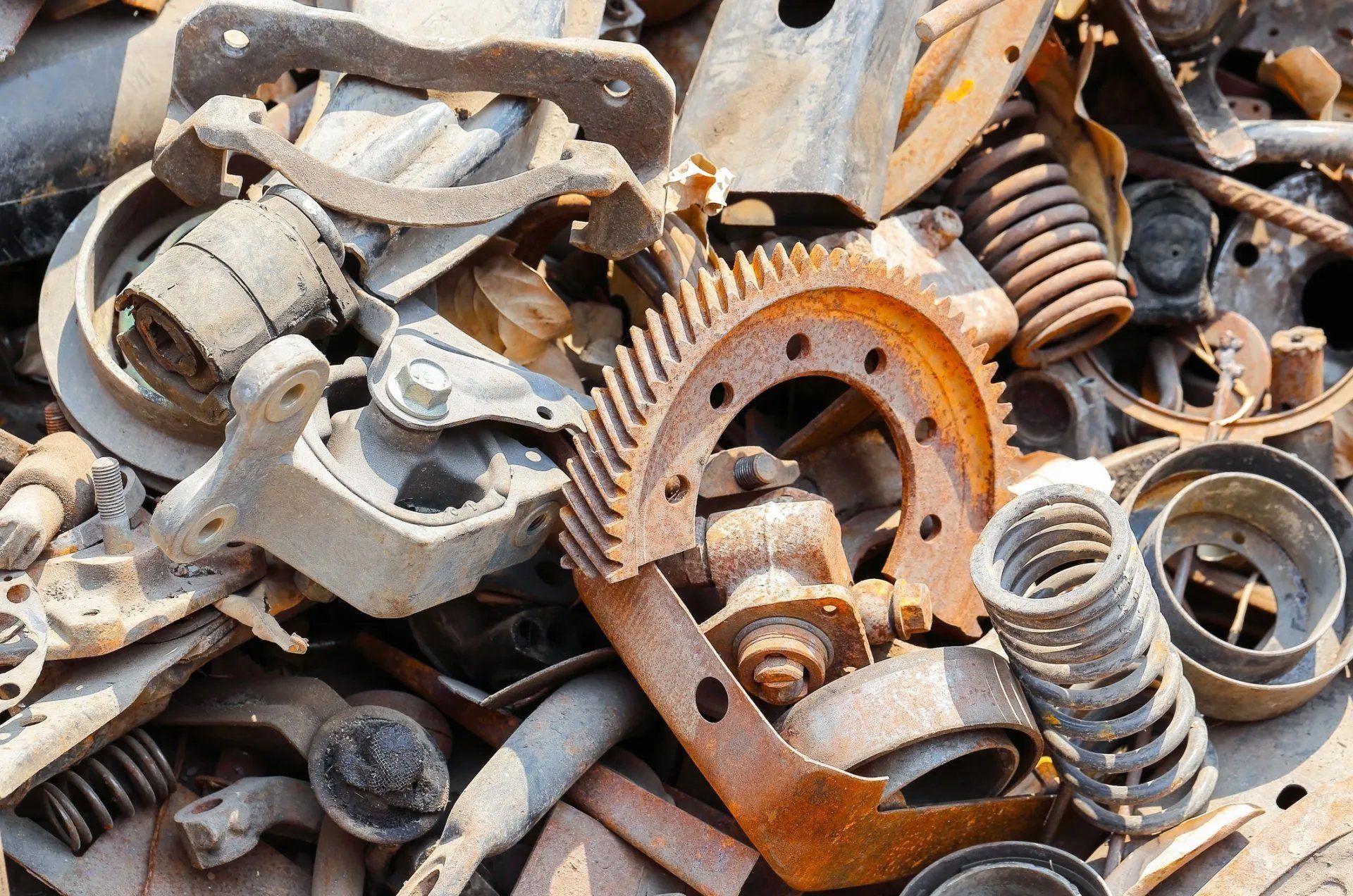 Pile of rusty metal scrap, including gears, springs, and bolts, tightly stacked together