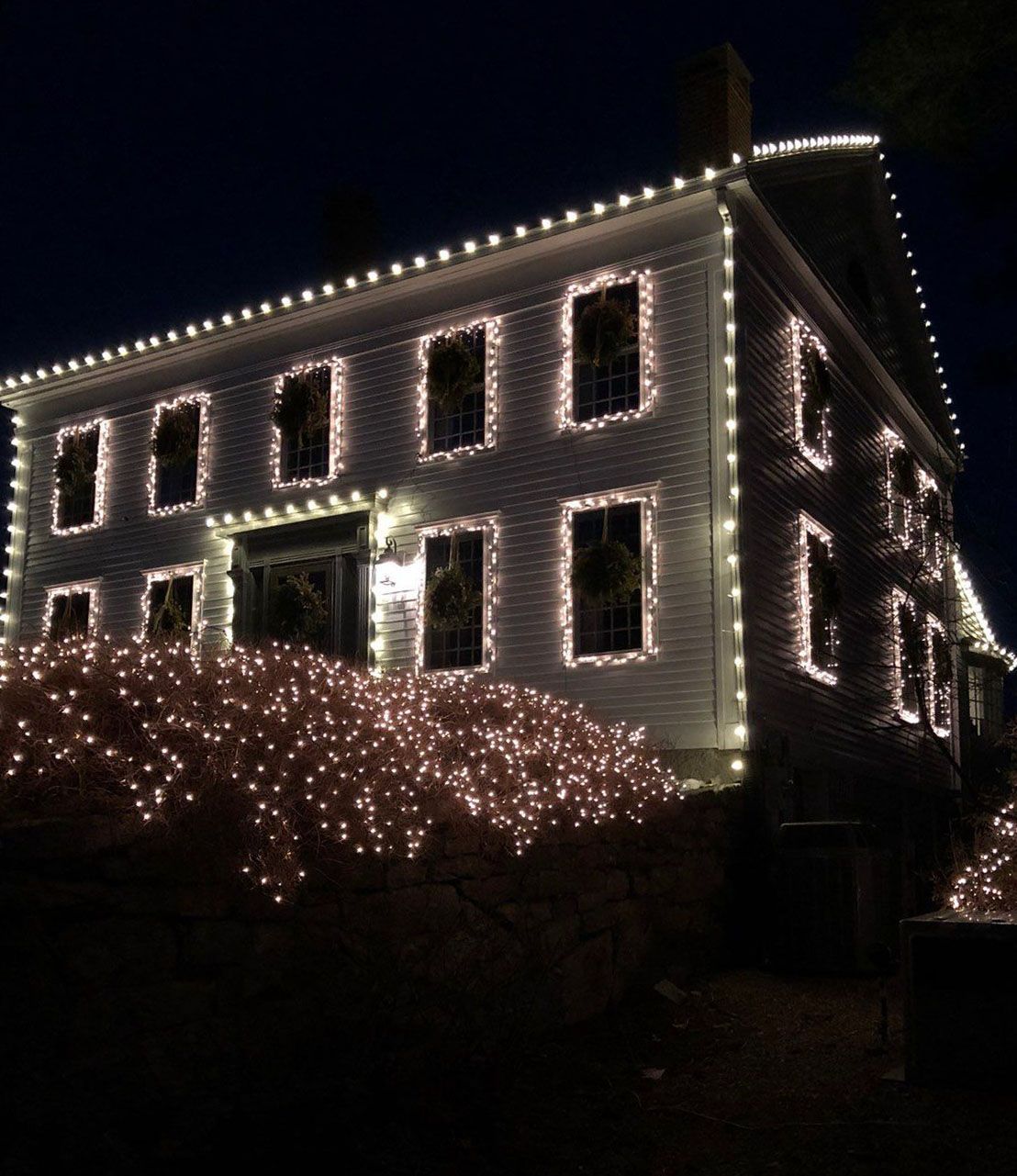 A large house is lit up with Christmas lights at night
