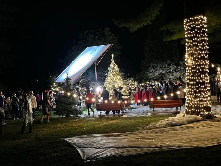A group of people are standing around a Christmas tree at night.