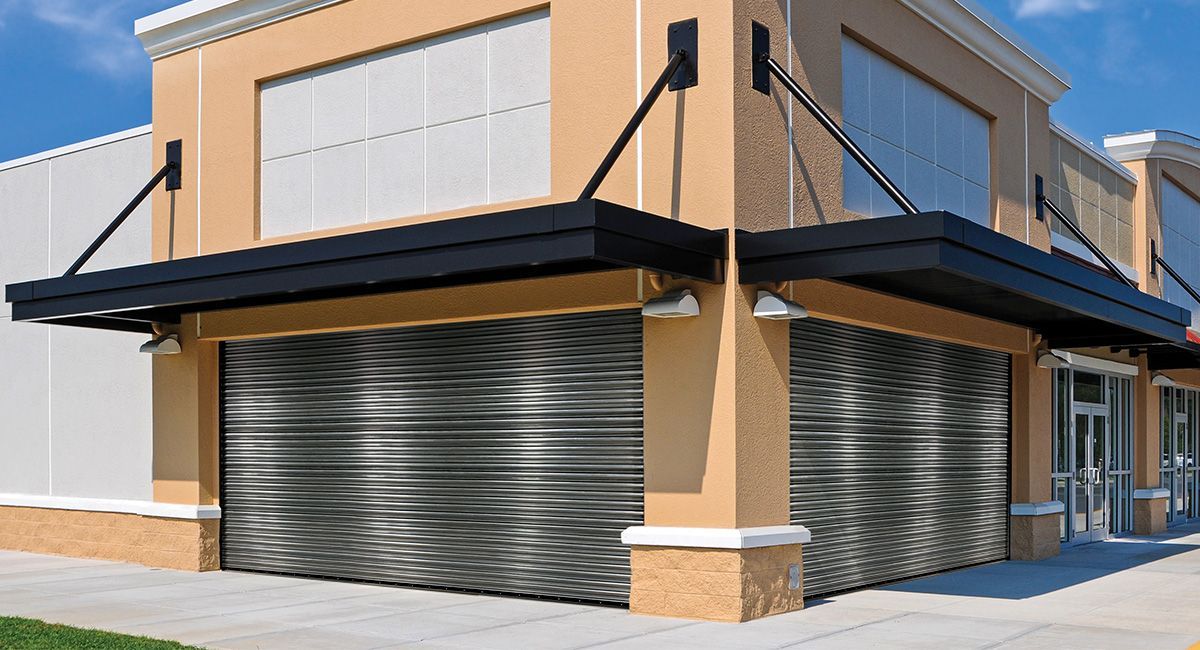 Building exterior with closed, patterned security shutters; awnings above windows.