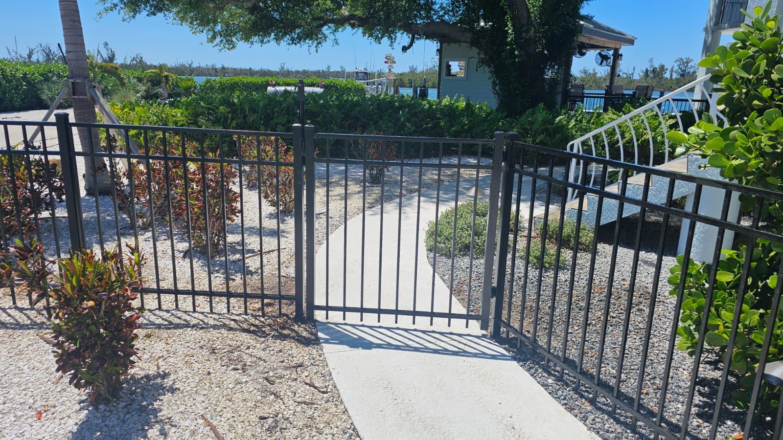 A metal fence surrounds a walkway leading to a house.