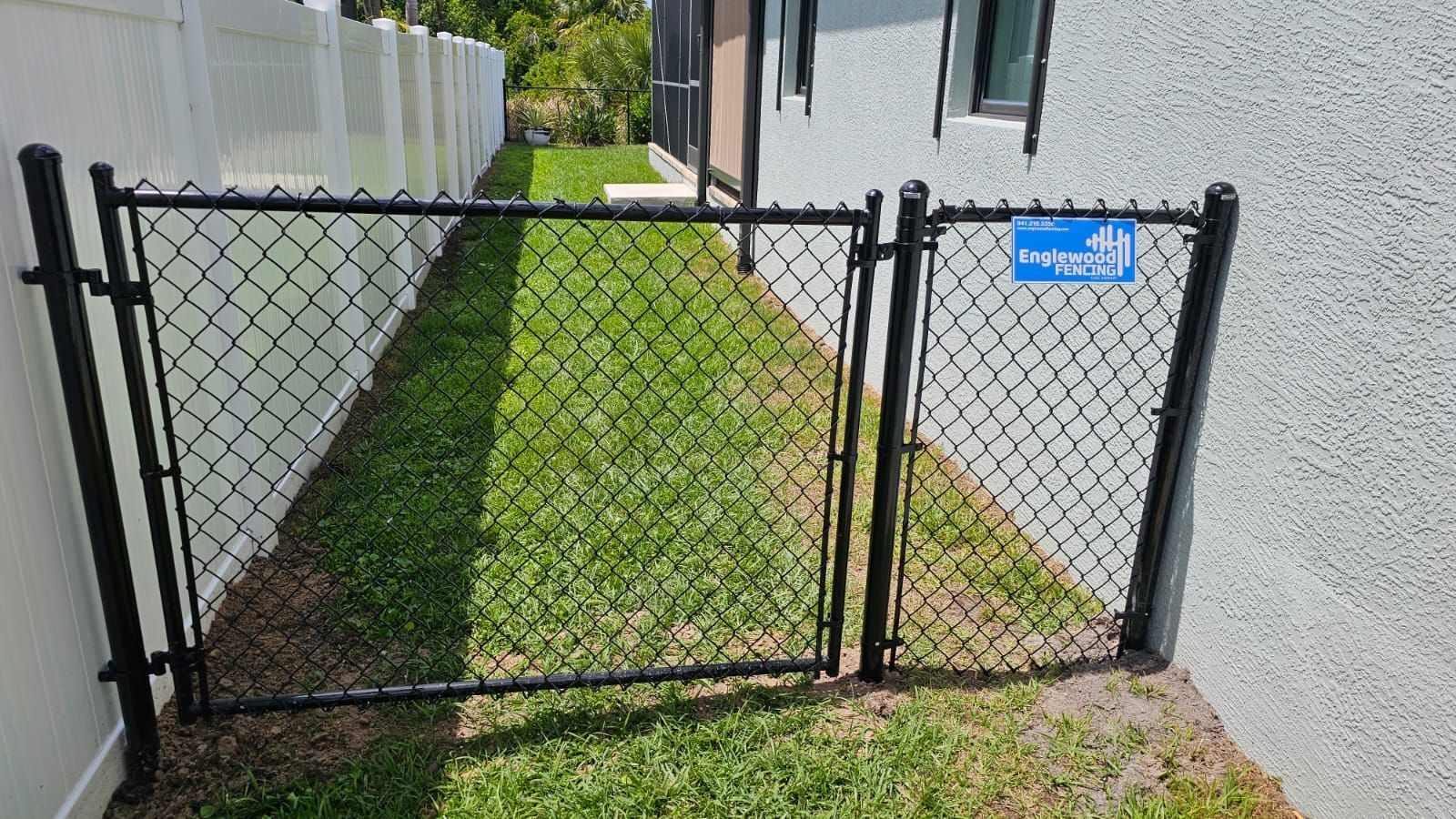 A chain link fence with a gate in the backyard of a house.