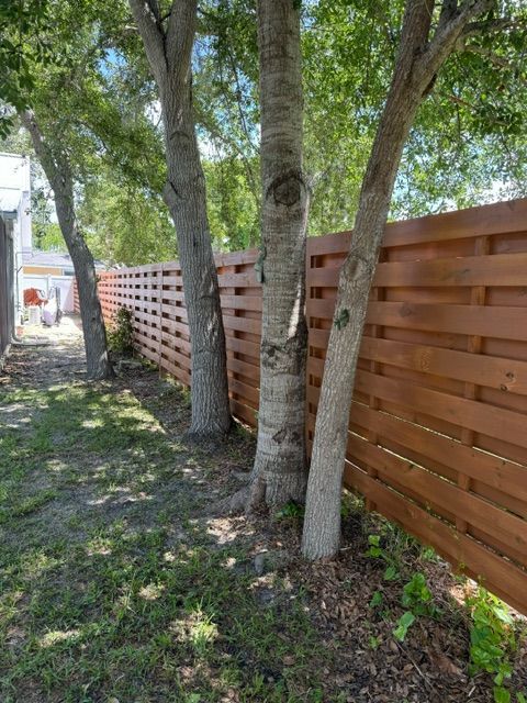 A wooden fence surrounded by trees in a yard.