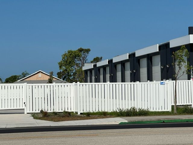 A white picket fence surrounds a row of houses.