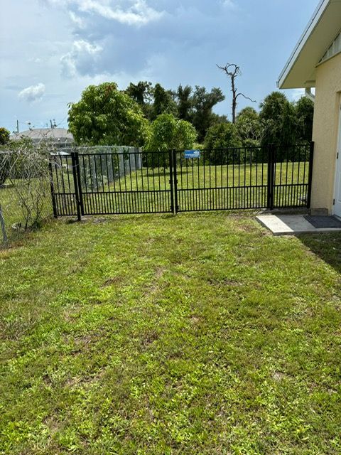 A lush green yard with a fence and a house in the background.