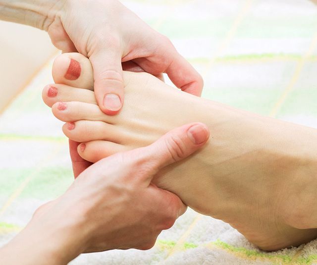 Hands performing a gentle massage on a person's foot.