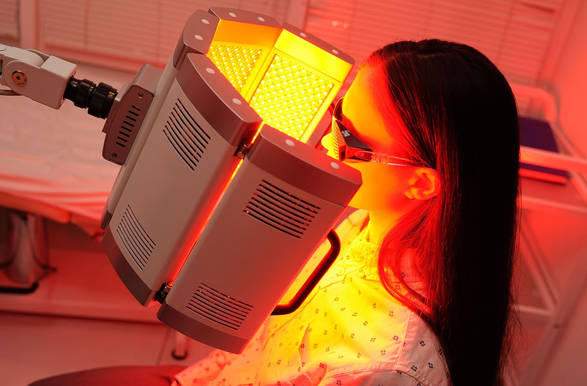 A person receiving red light therapy from a medical device in a clinical setting