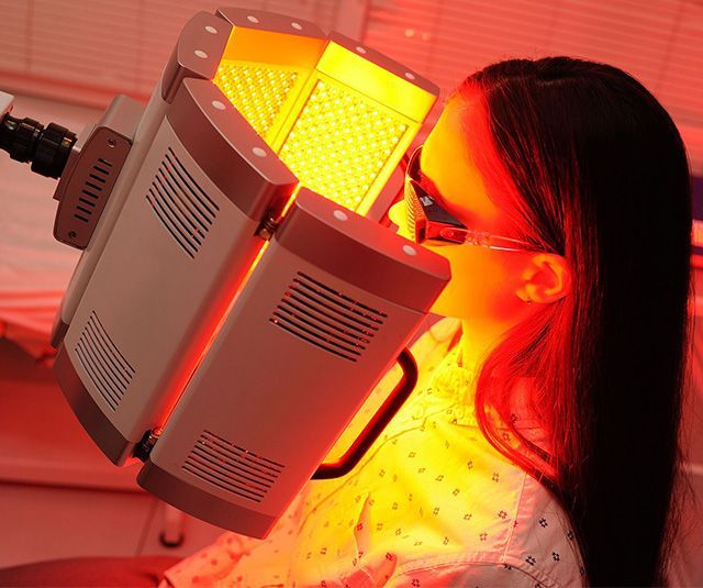 Person using a bright red light therapy mask on the face indoors