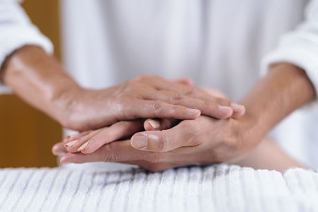 Hands gently stacked on a white towel during a massage or spa treatment