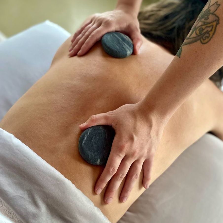 A woman is getting a massage with rocks on her back