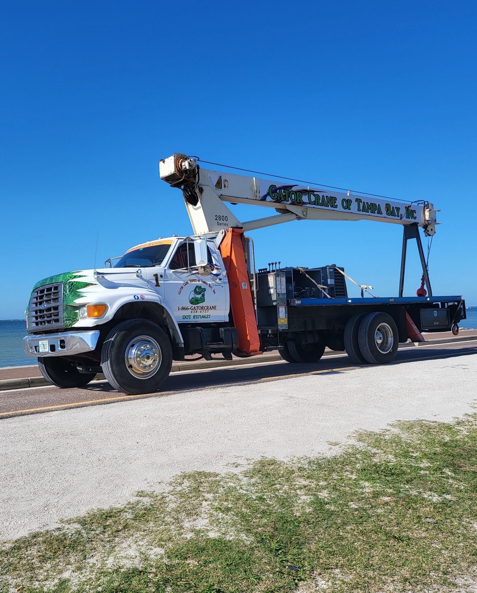 A truck with a crane on top of it is parked on the side of the road.