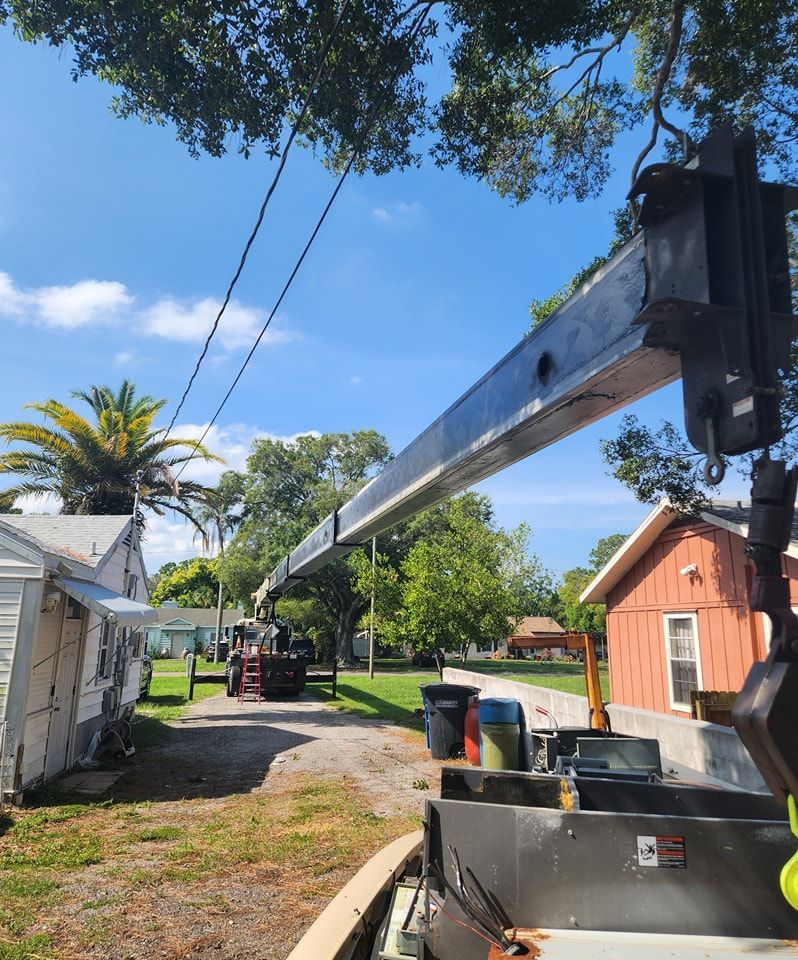A crane is being used to remove a tree in front of a house