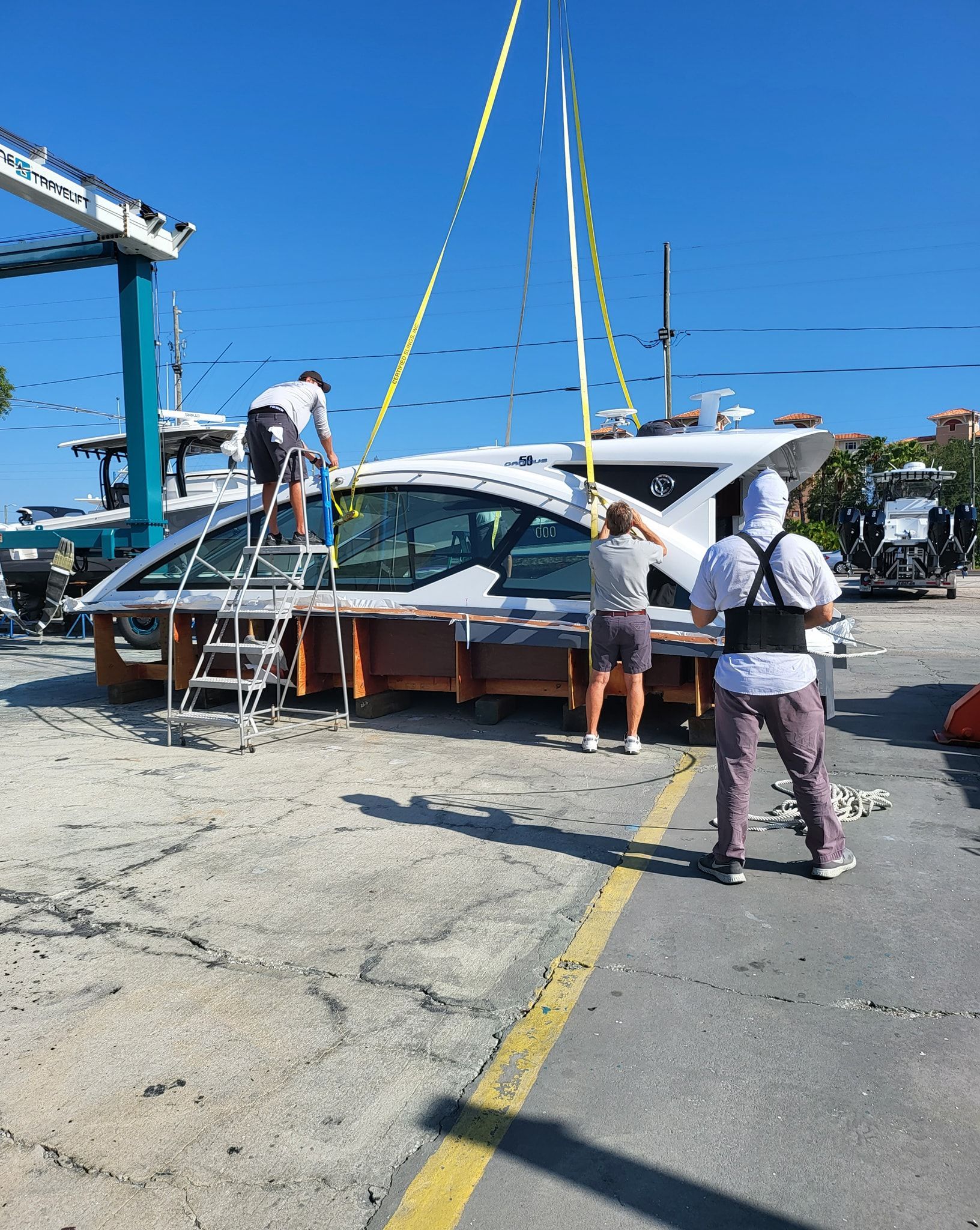 A boat is being lifted by a crane in a parking lot