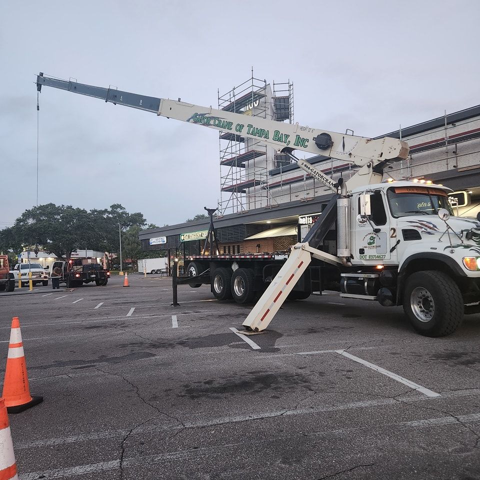 A white truck with a crane on the back is parked in a parking lot
