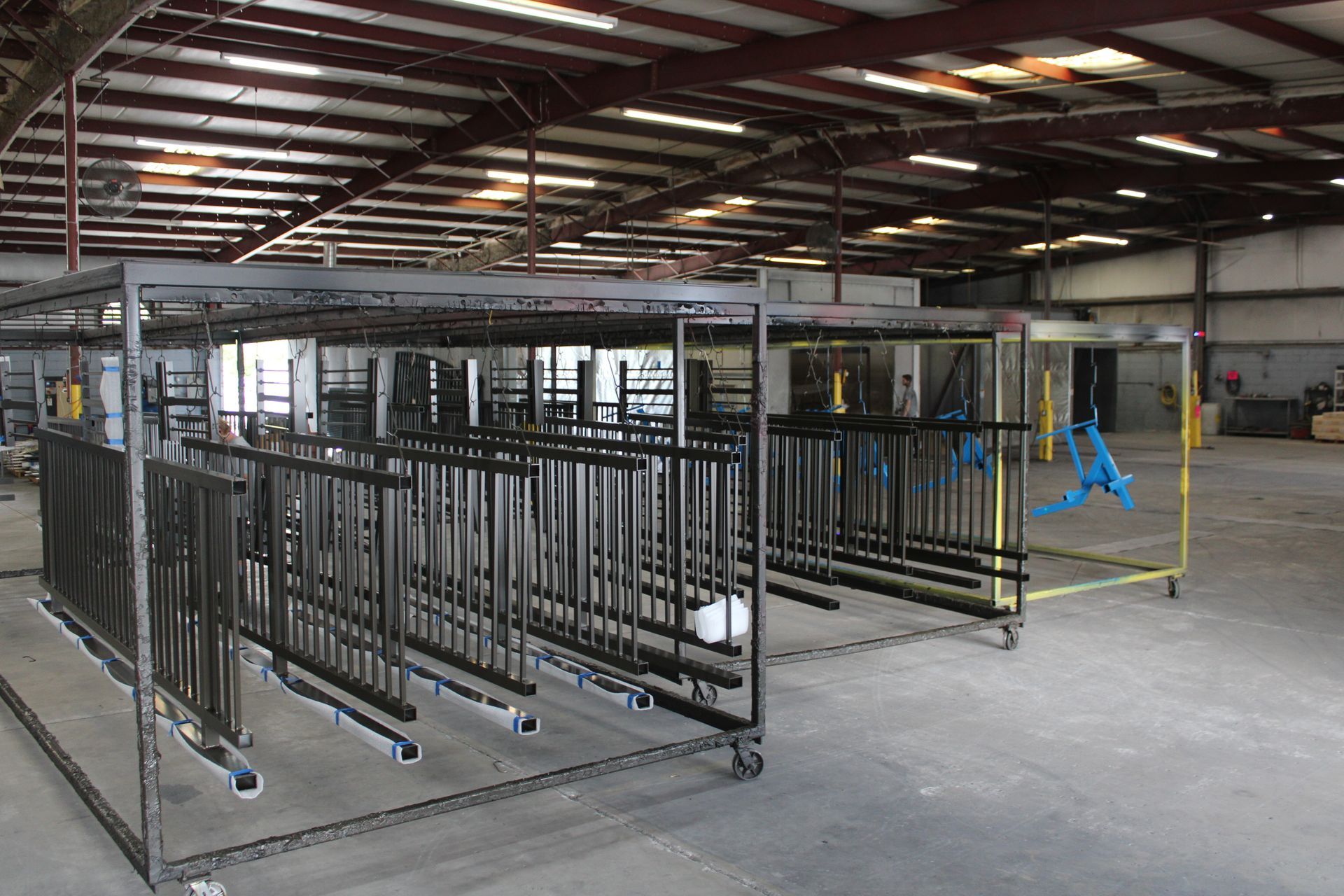 Metal railings on wheeled racks inside a large industrial warehouse.