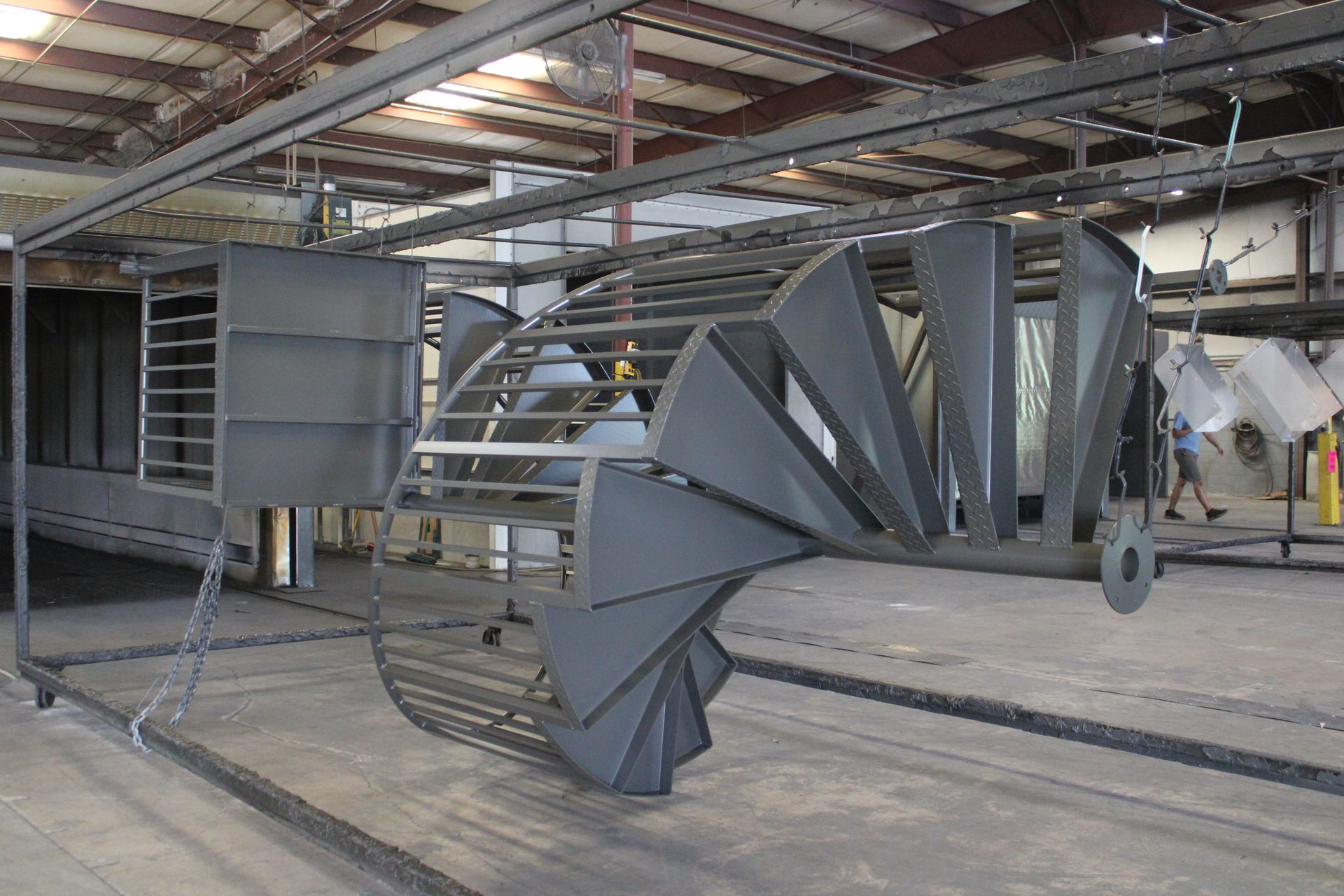 Metal parts on a conveyor system in a factory, freshly painted dark gray.