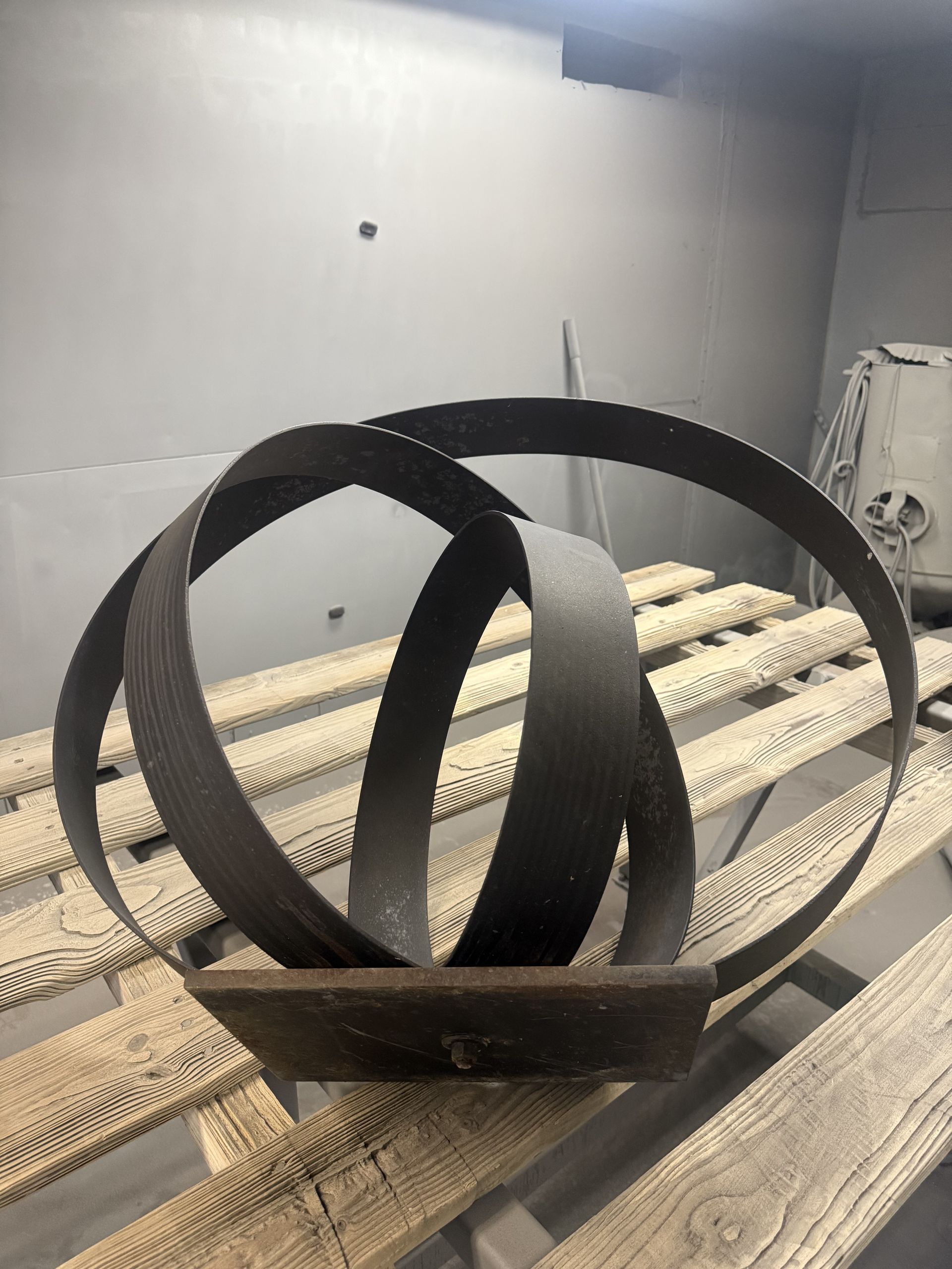 Abstract black metal sculpture with curved loops on a wooden surface indoors
