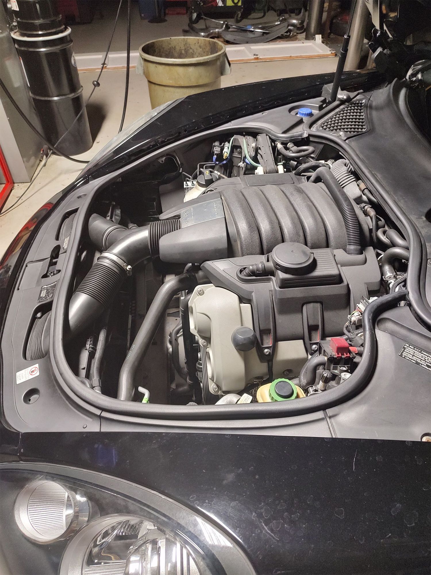 Black car engine bay with exposed engine and components.