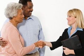 Older couple shaking hands with a woman in a business suit; white background