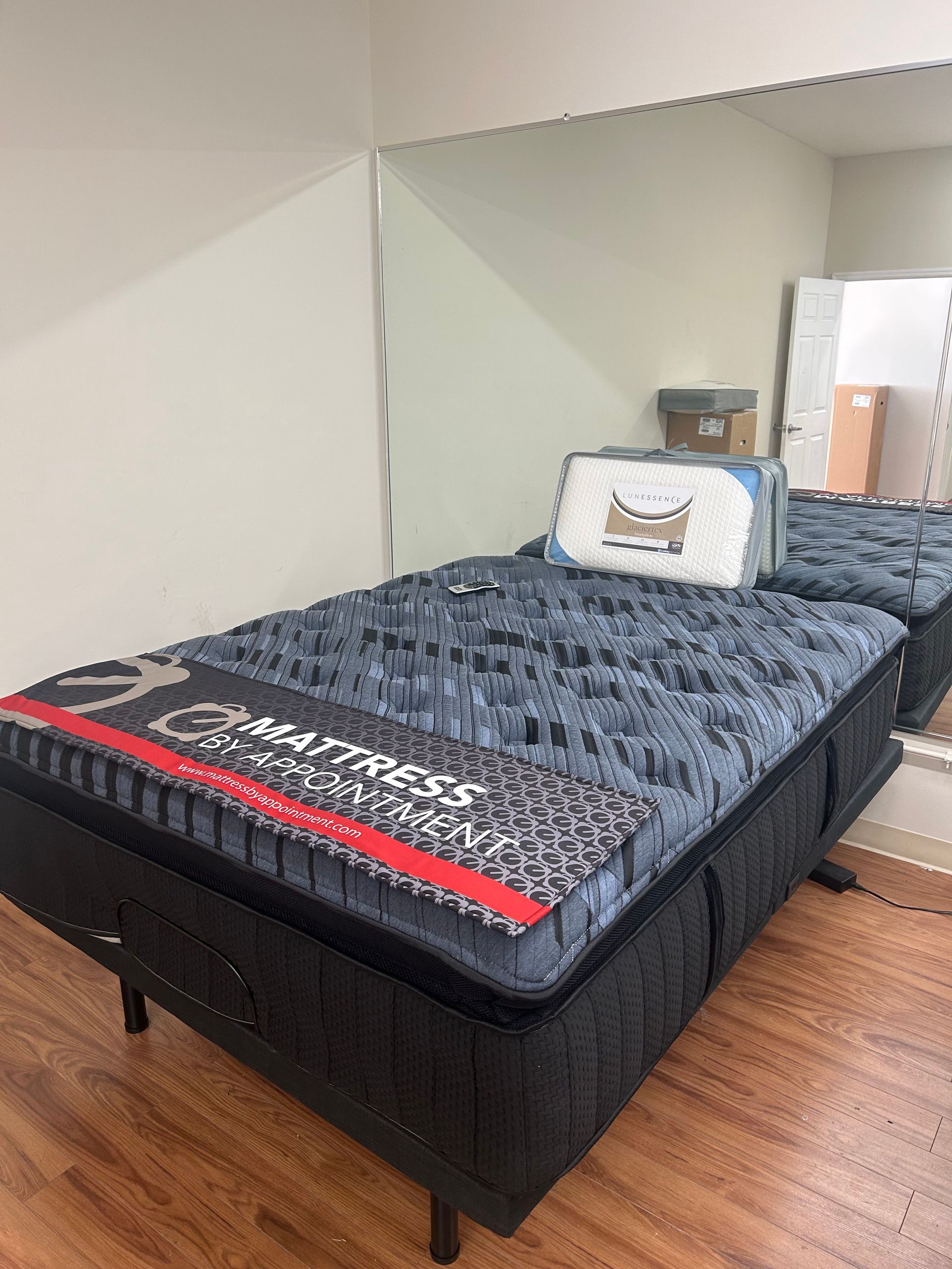 Black bed with patterned blue top and red strip, in front of a mirror