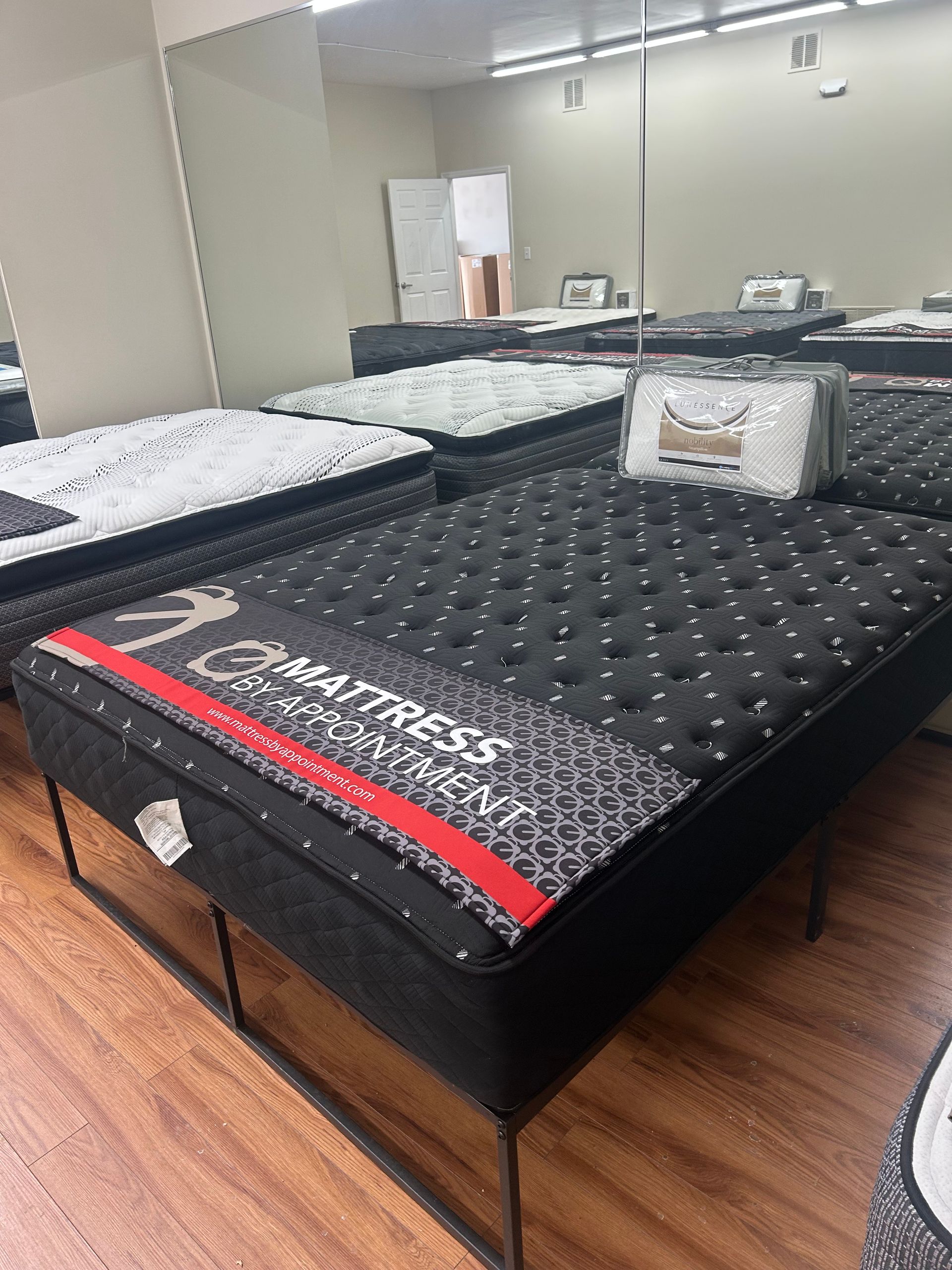 Mattresses on display in a brightly lit showroom with wooden floors