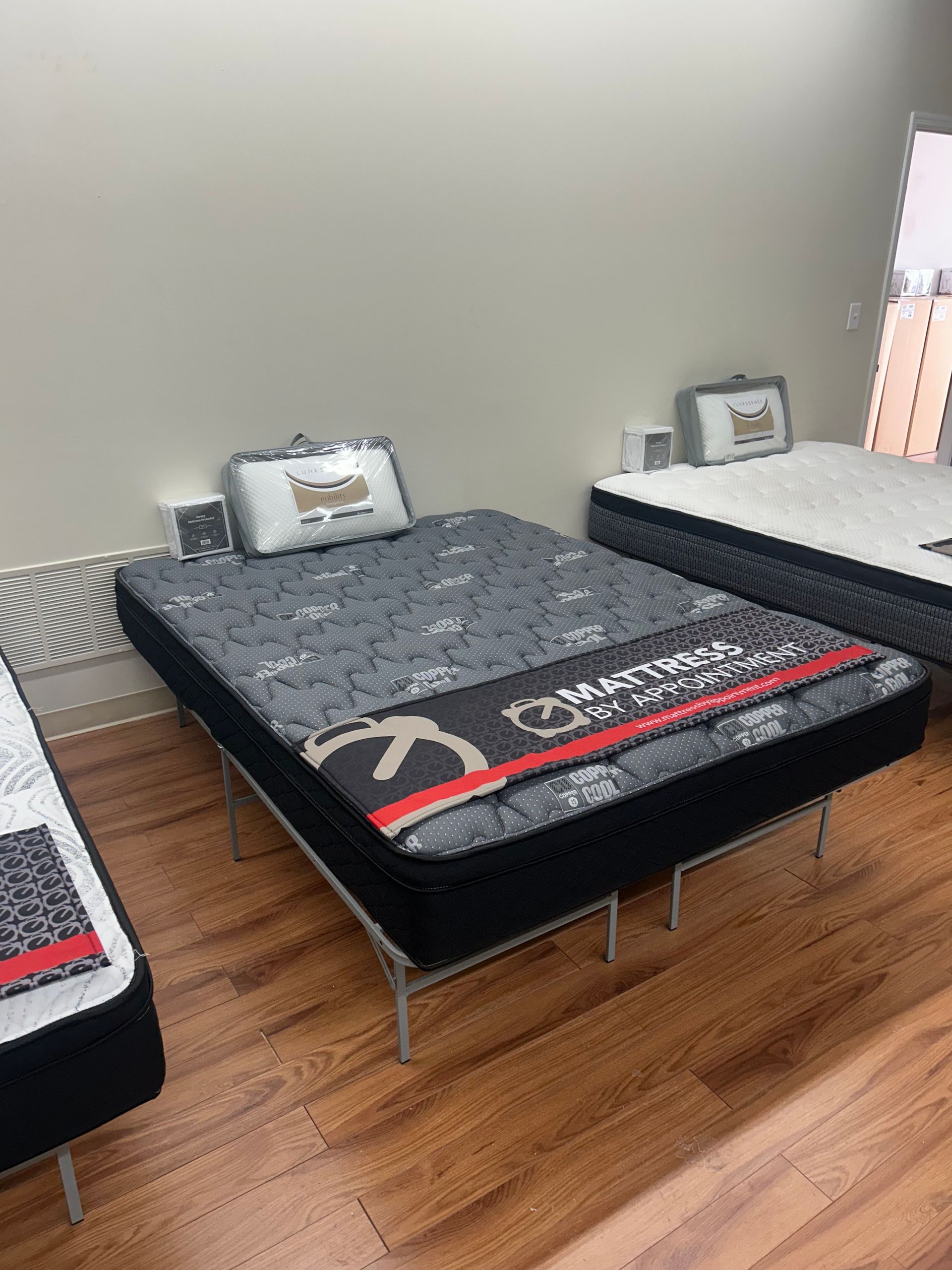 Mattresses on display in a store; black and white patterned bedding on metal frames