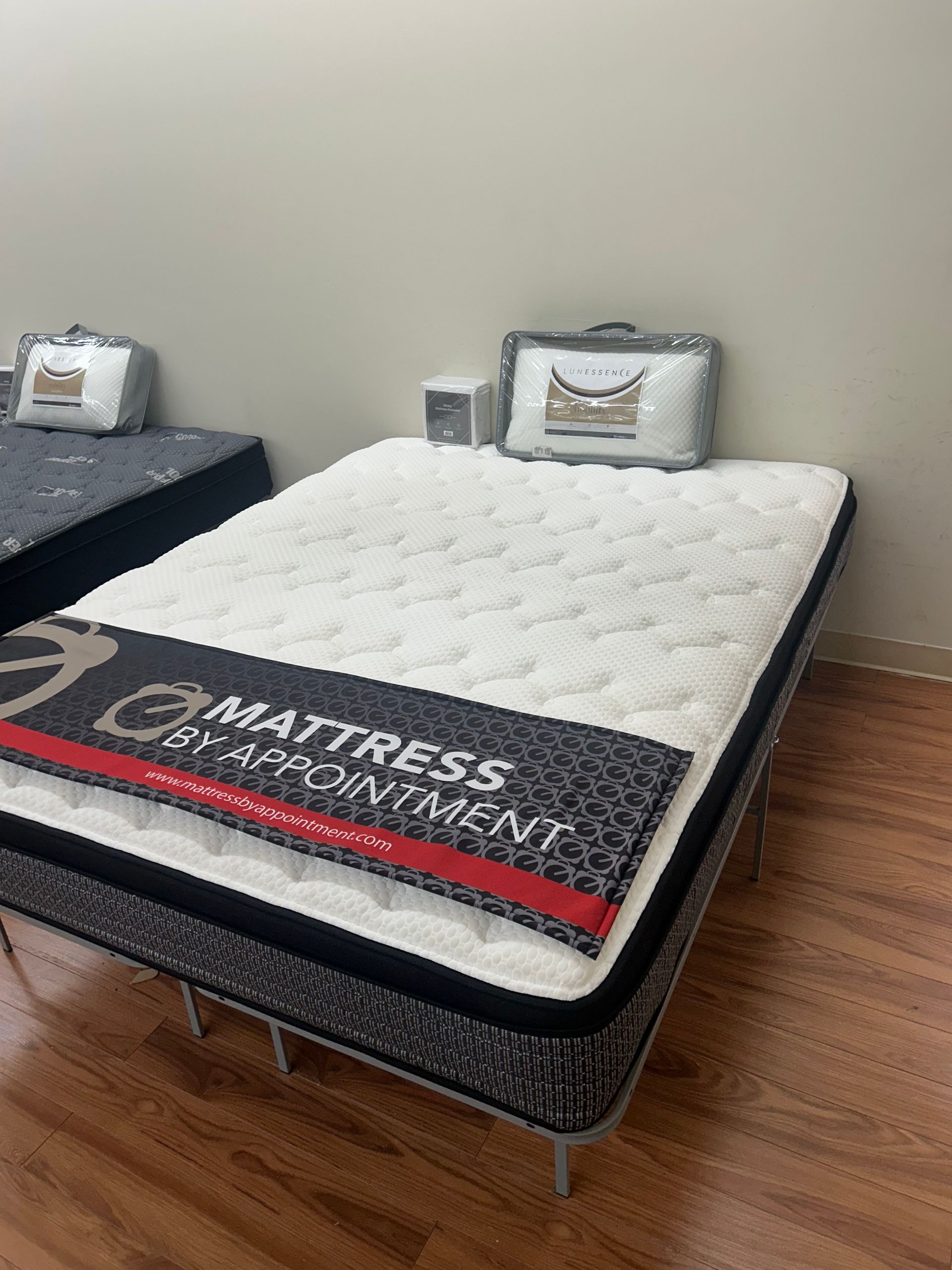Mattress display in a store. White quilted top with a black and white patterned border, with bedding