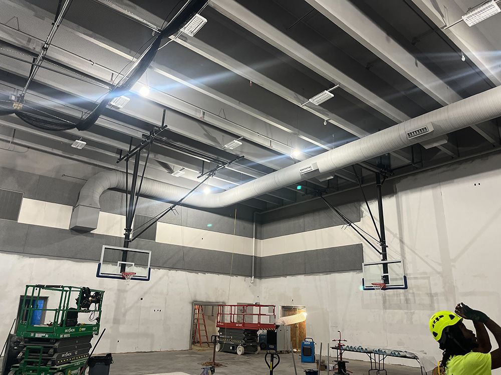 A basketball hoop is being installed in a gym.