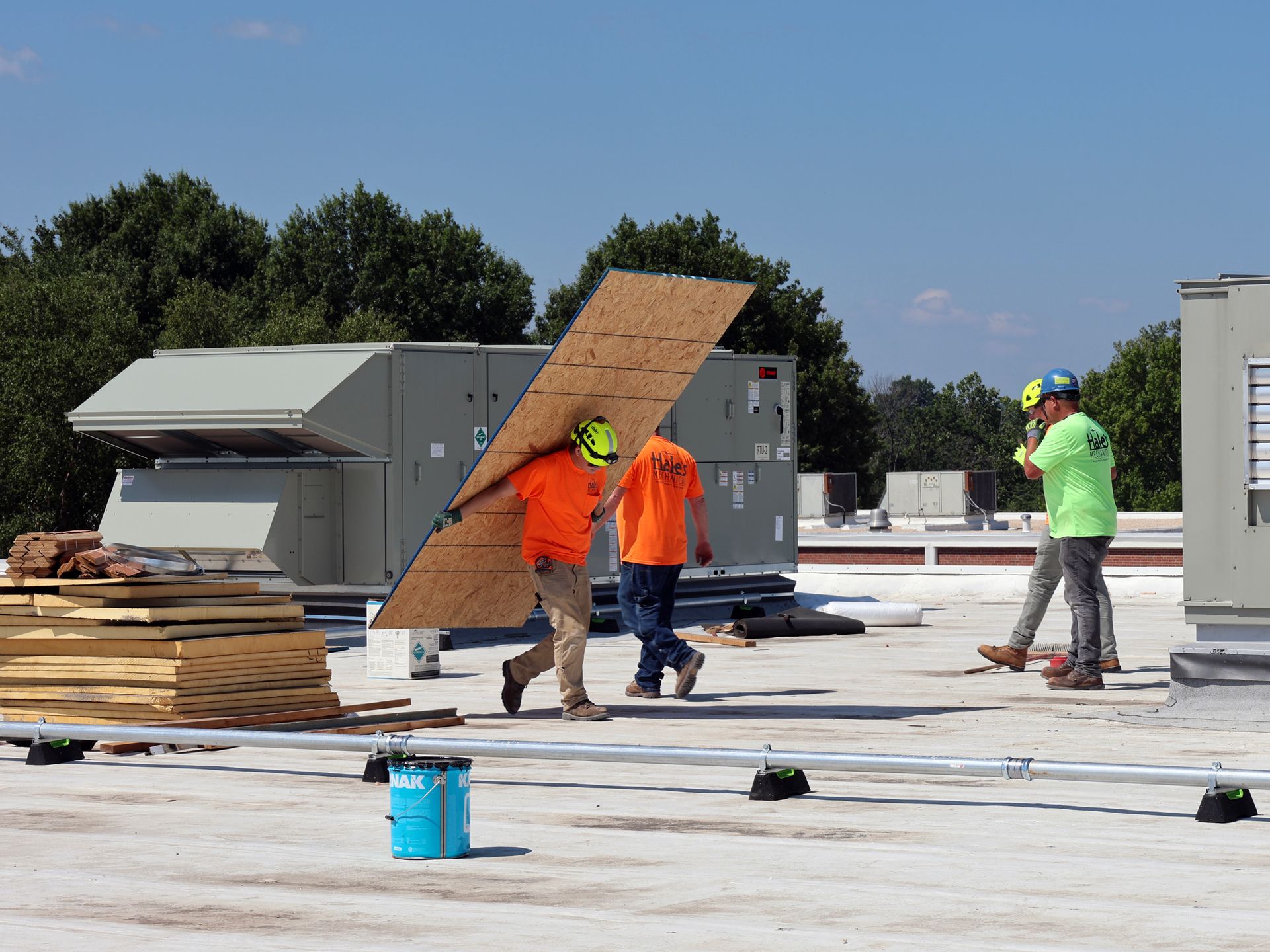 A man is carrying a large piece of plywood on his back.