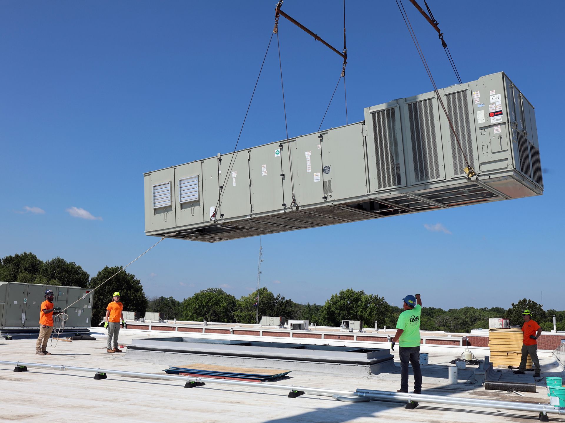 A large box is being lifted by a crane on top of a roof.