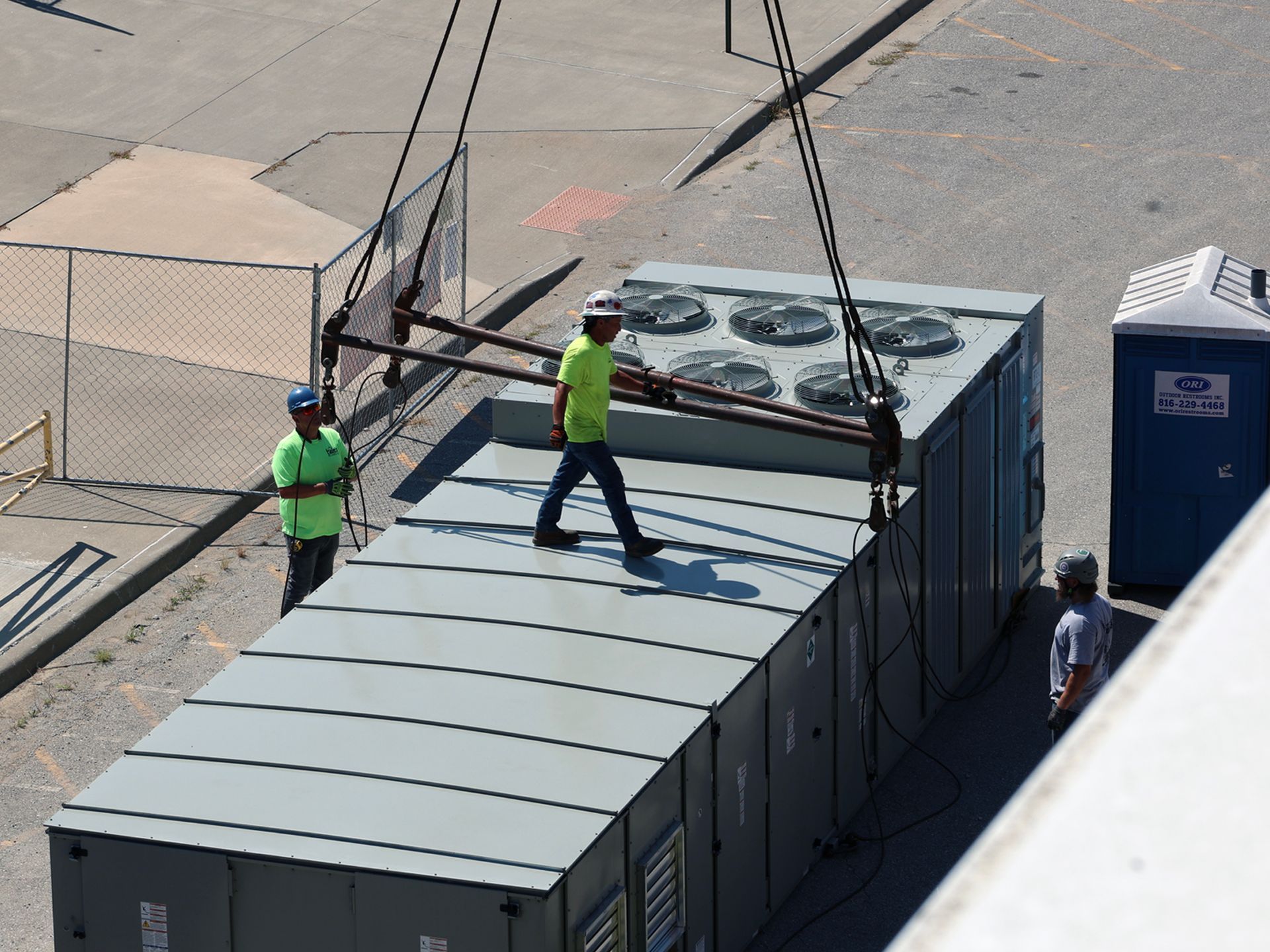 A man in a yellow shirt is standing on top of a large box