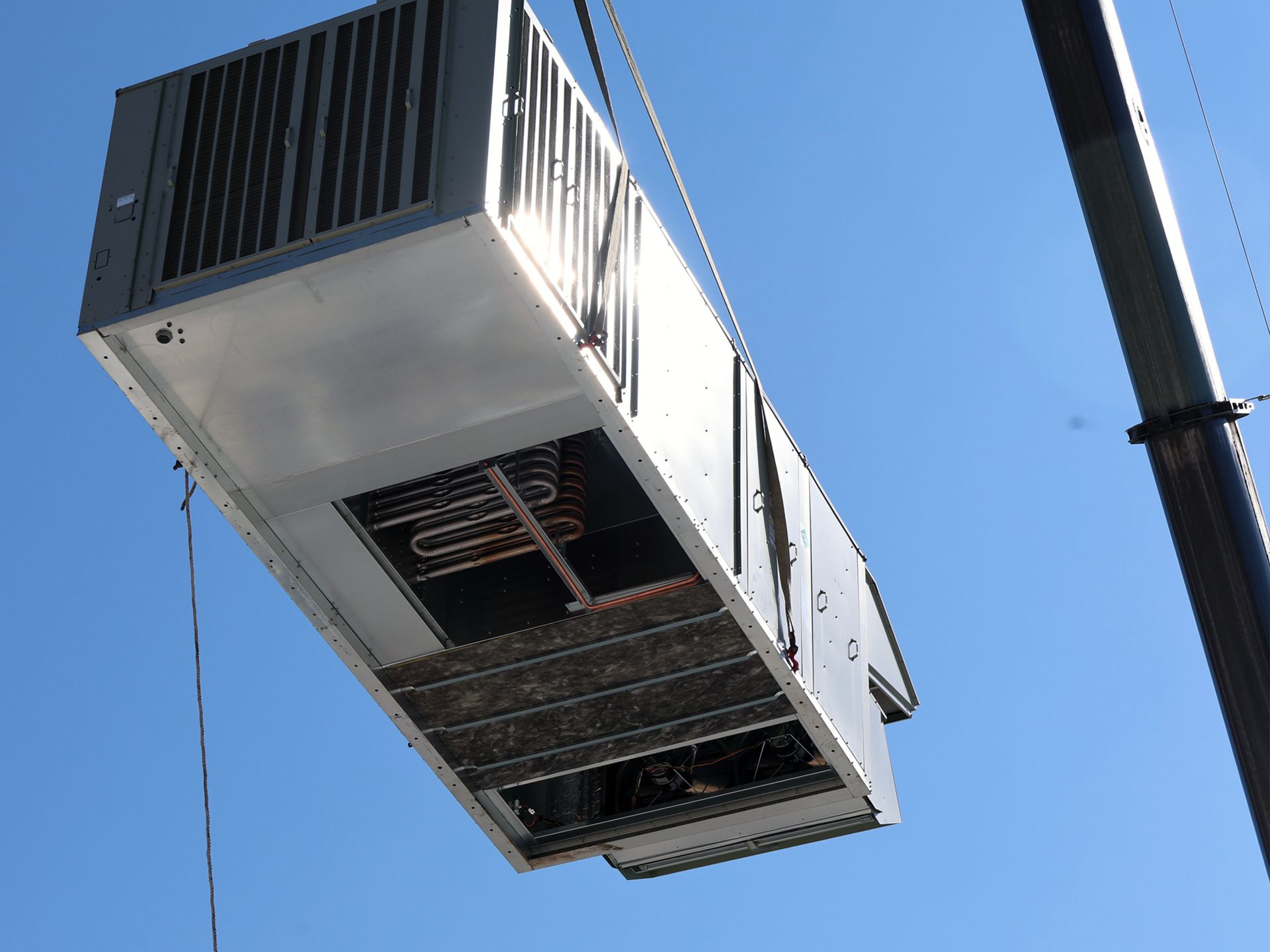 An air conditioner is being lifted into the air by a crane