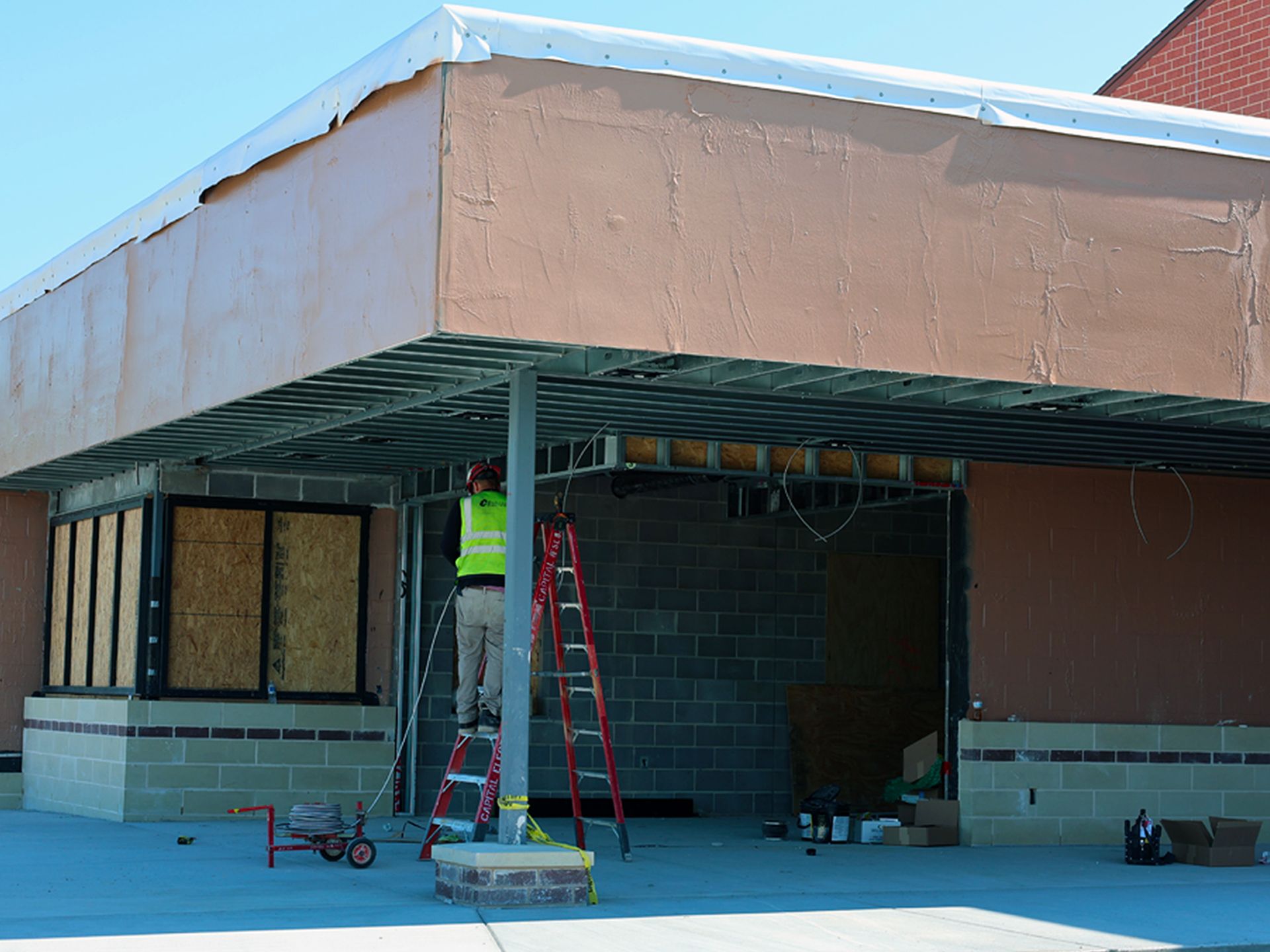 A man standing on a ladder in front of a building under construction