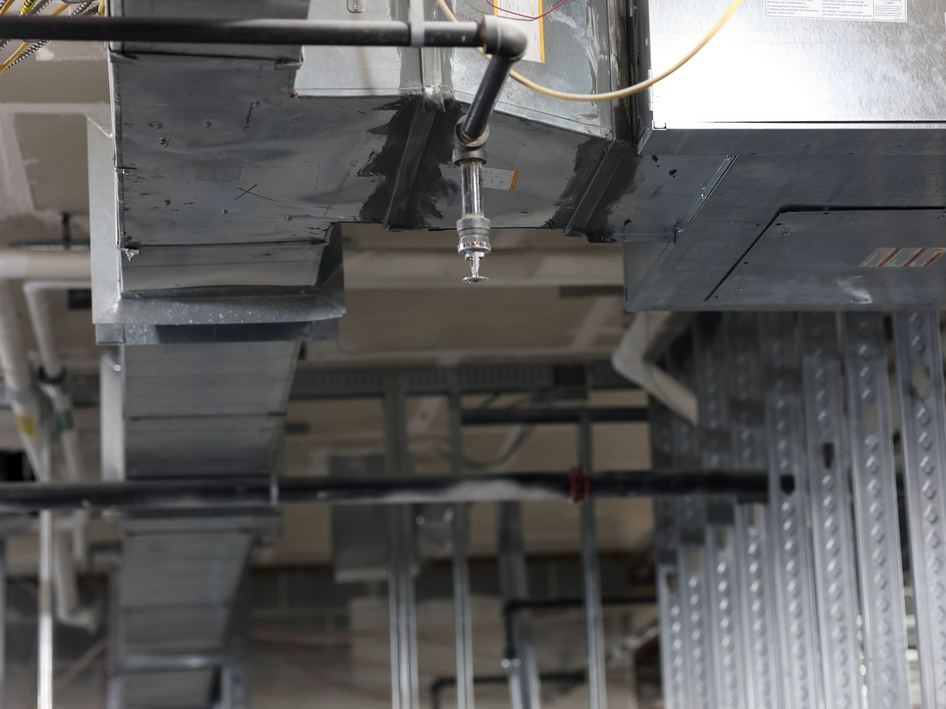 There are a lot of pipes hanging from the ceiling of a building.