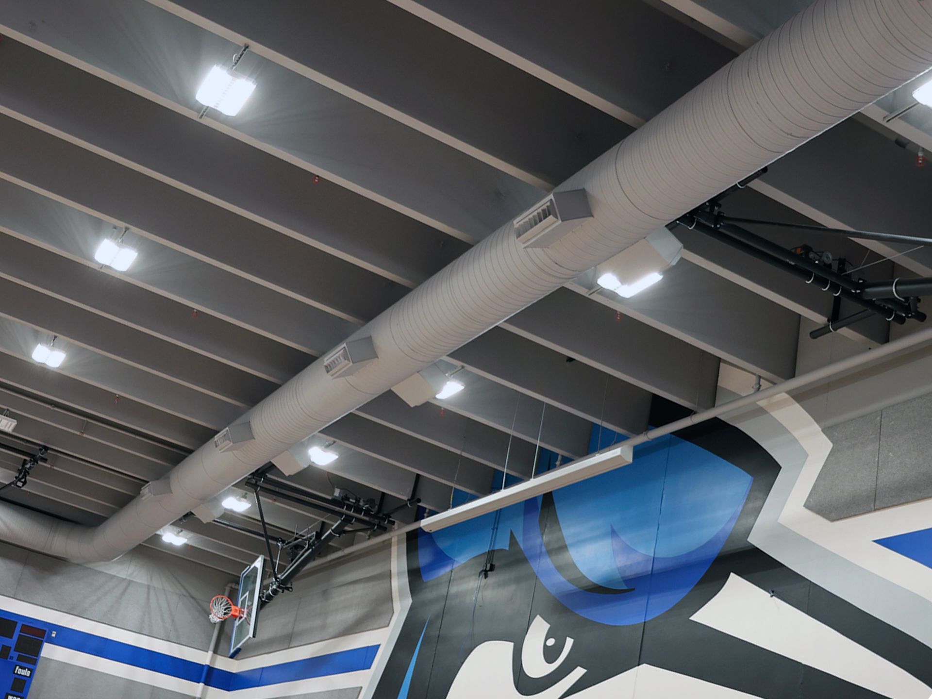 A basketball court with a mural on the wall and a basketball hoop.