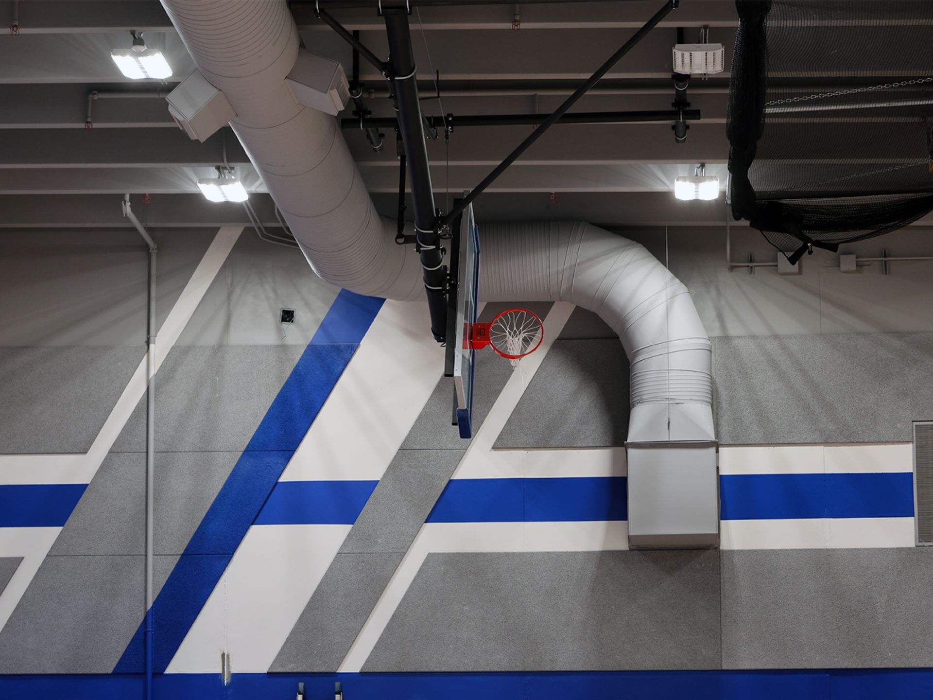 A basketball hoop in a gym with blue and white stripes on the wall