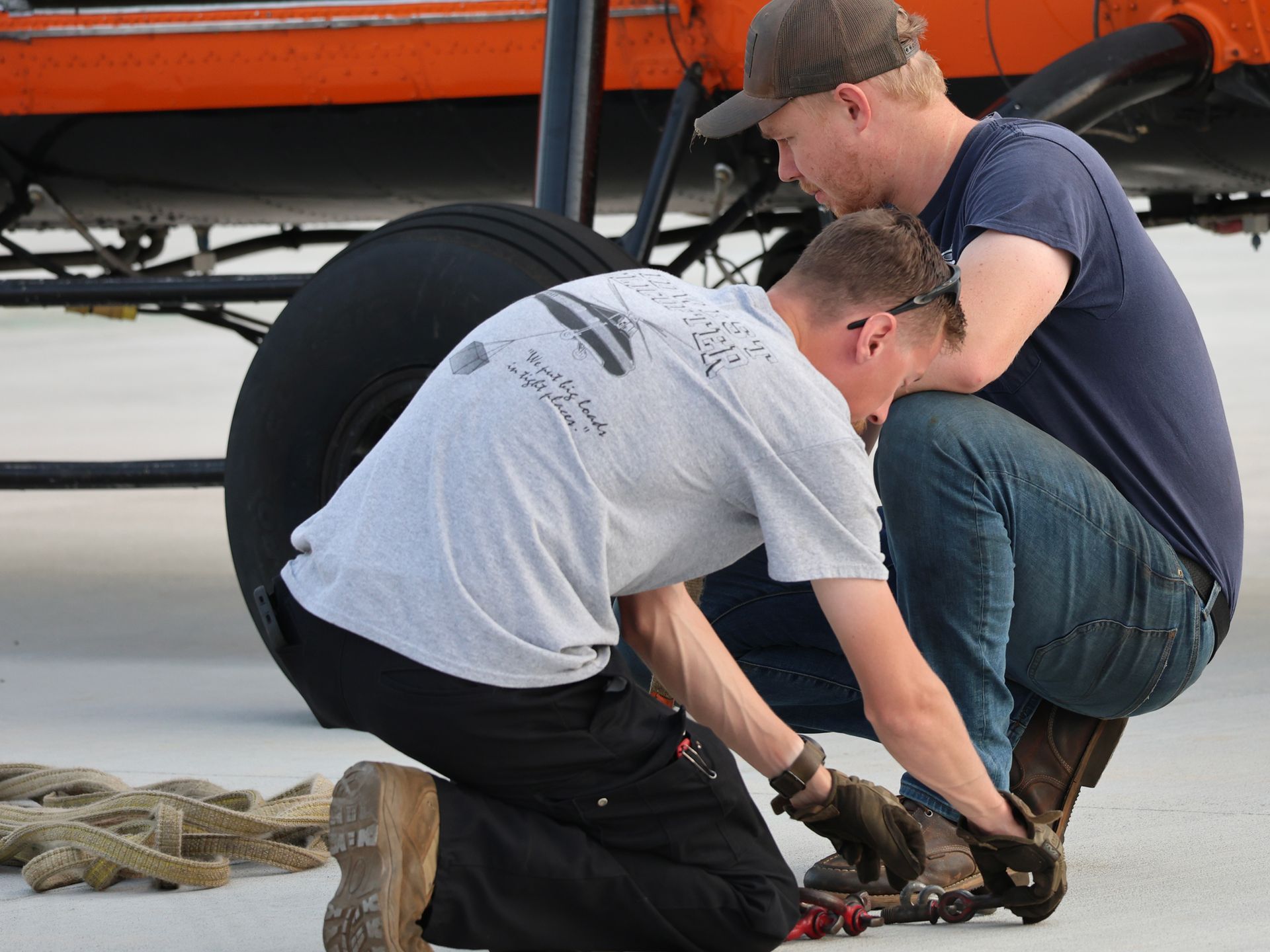 Two men are working on a tire on the ground