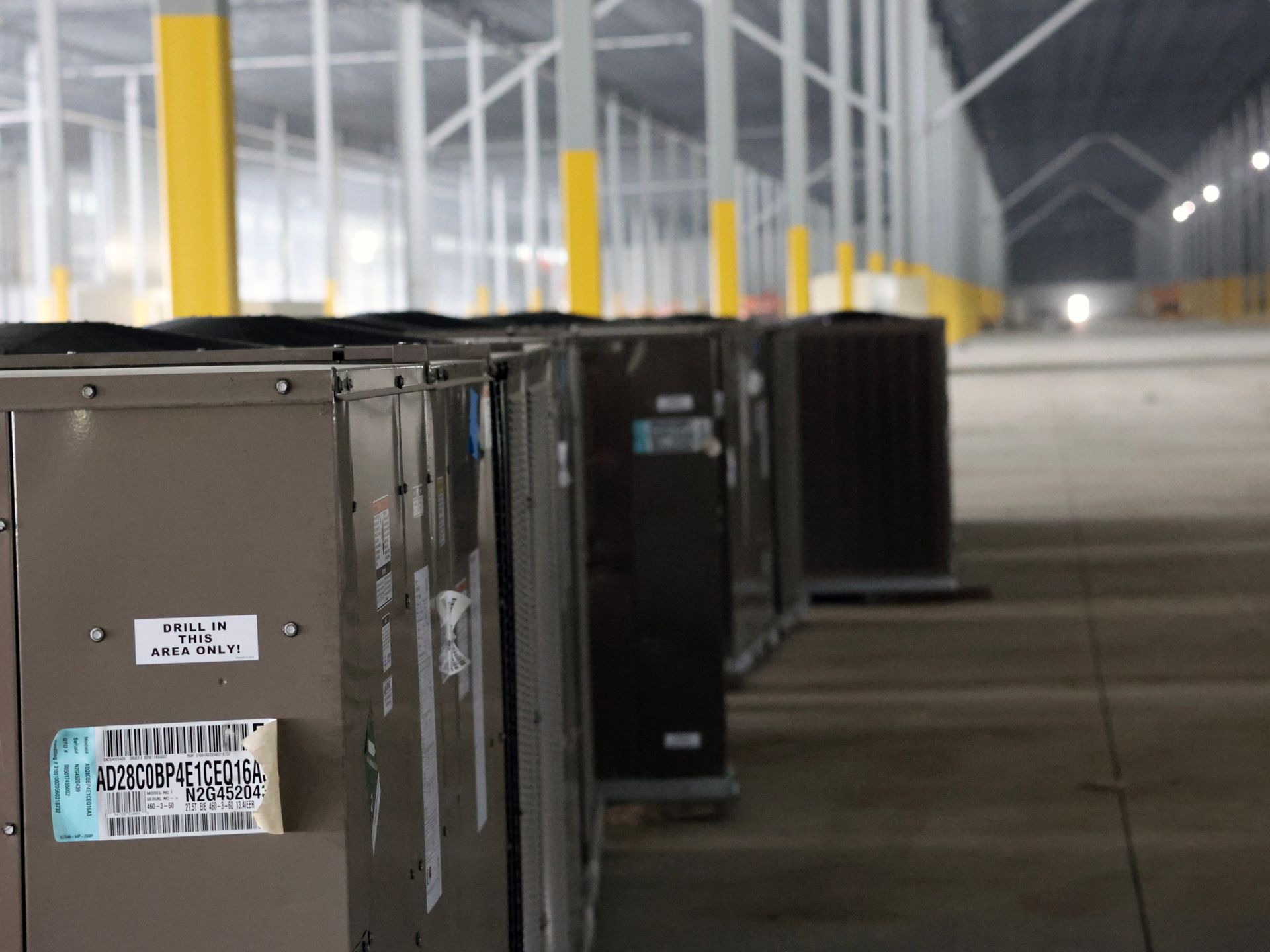 A row of air conditioners are lined up in a warehouse