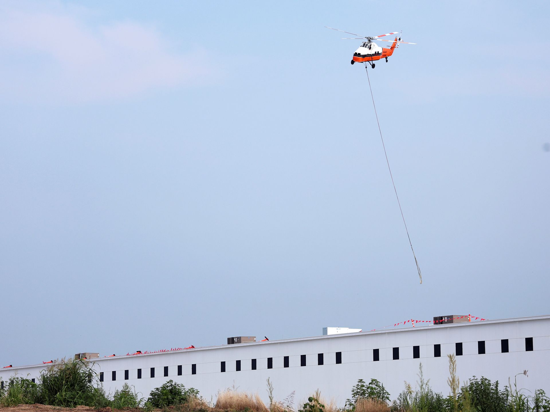 A helicopter is flying over a white building