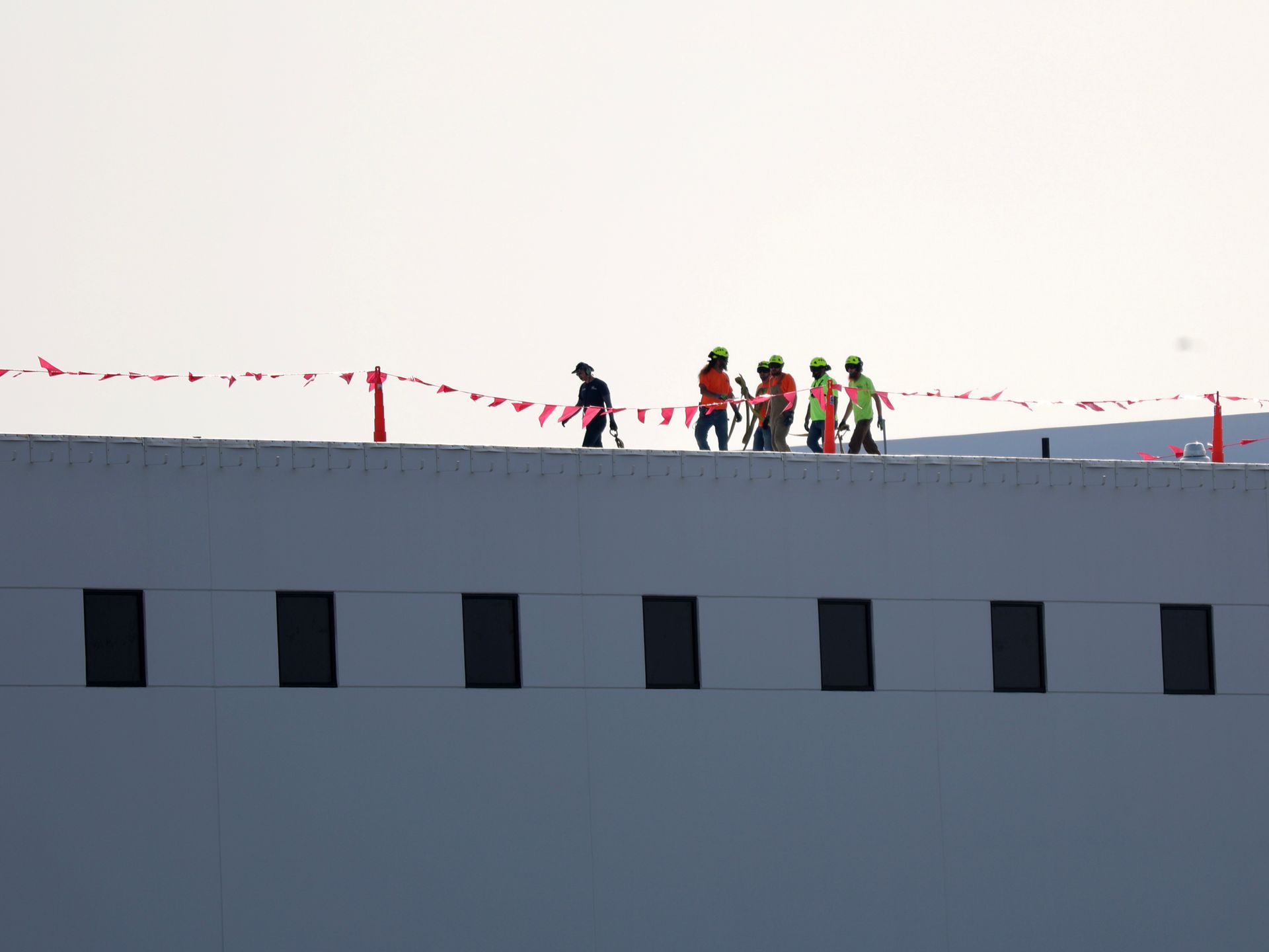 A group of construction workers are walking on the roof of a building.
