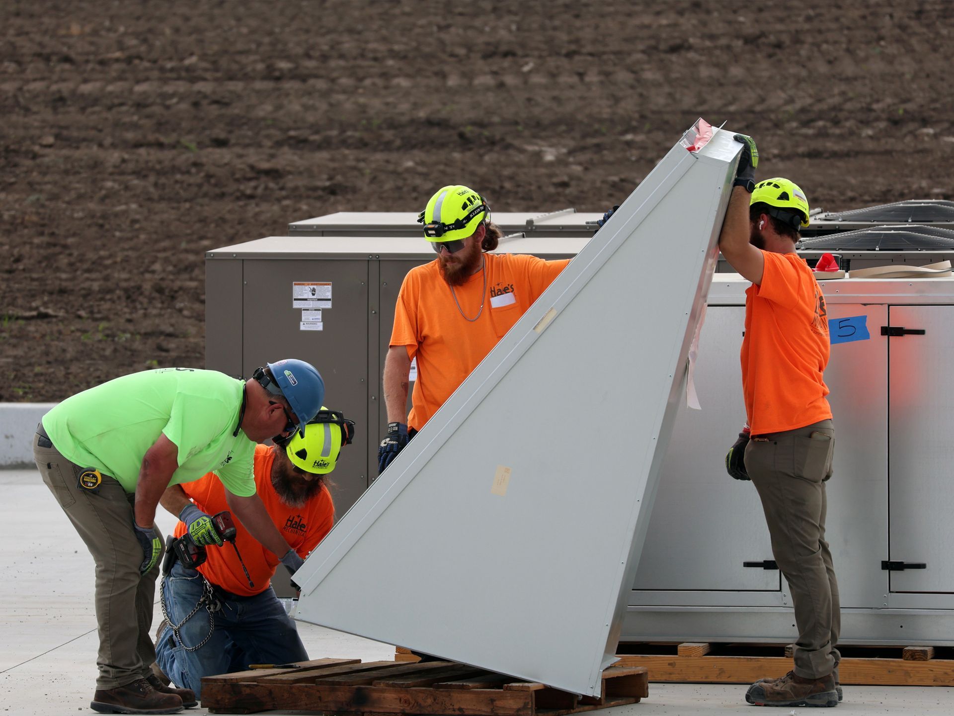 A group of construction workers are working on a large piece of metal.