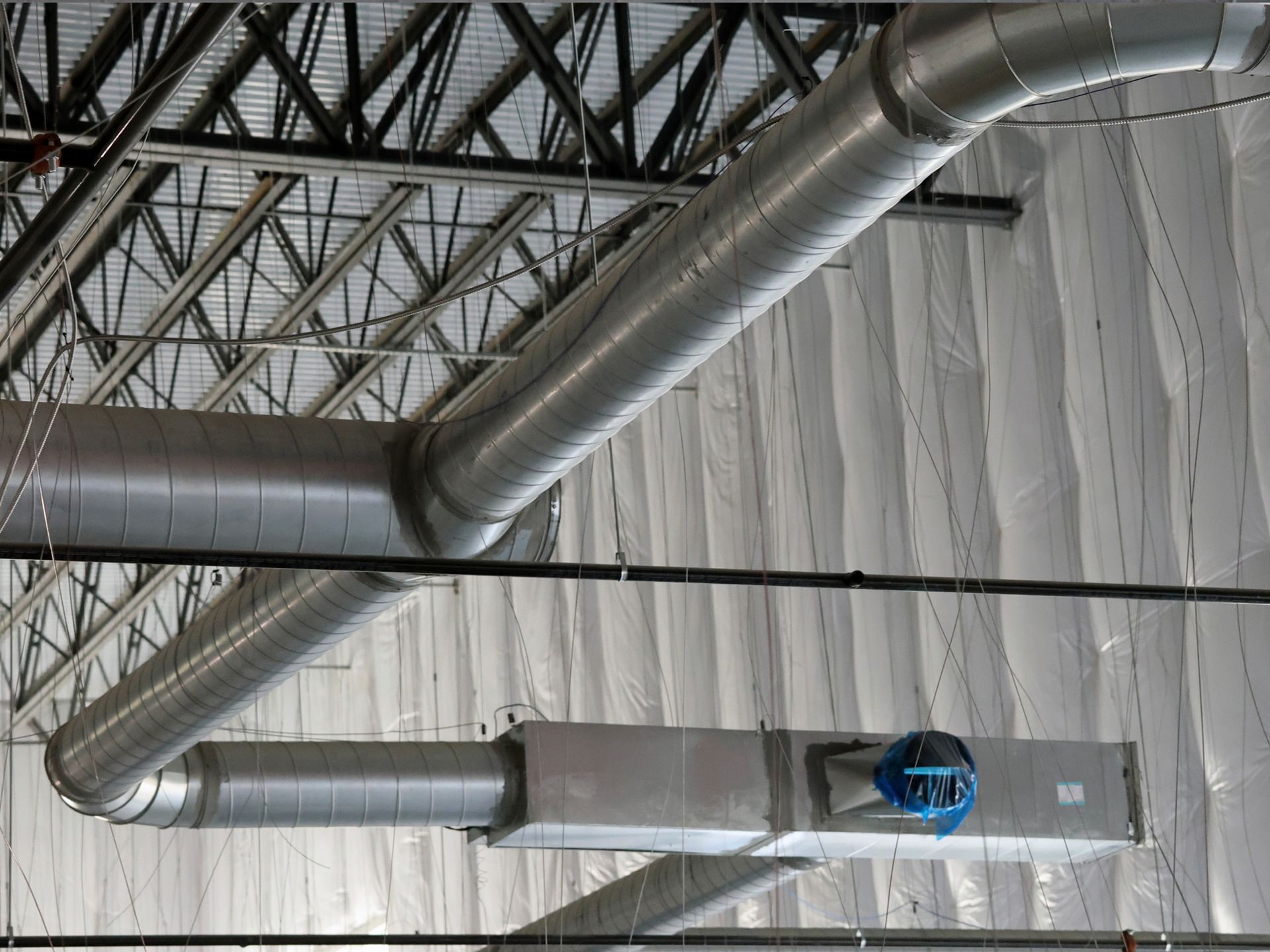 There are a lot of pipes hanging from the ceiling of a building.