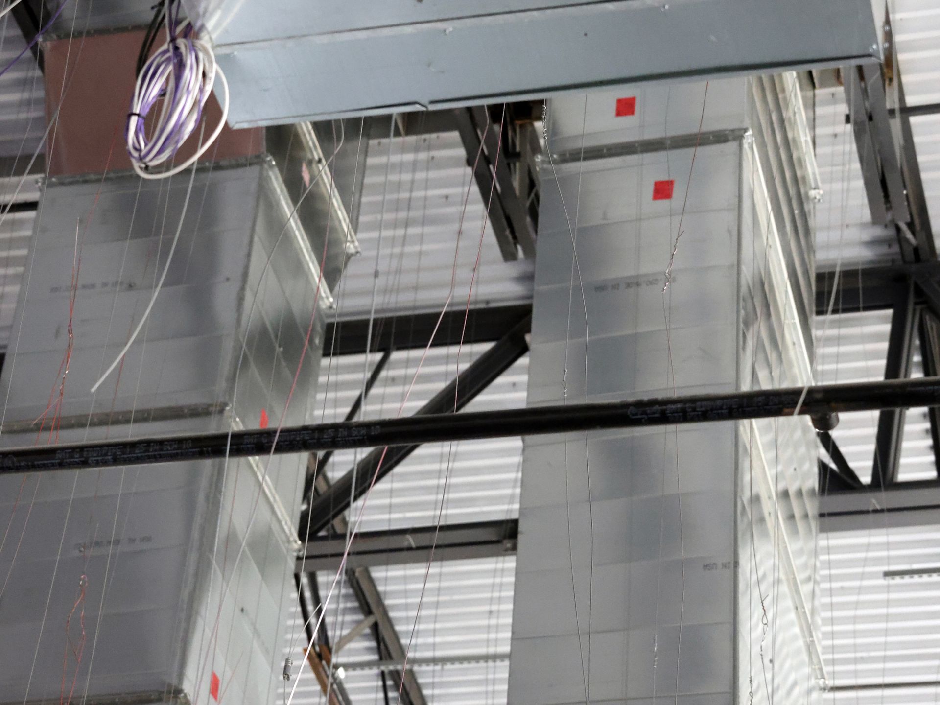 The ceiling of a building with a lot of ducts hanging from it.