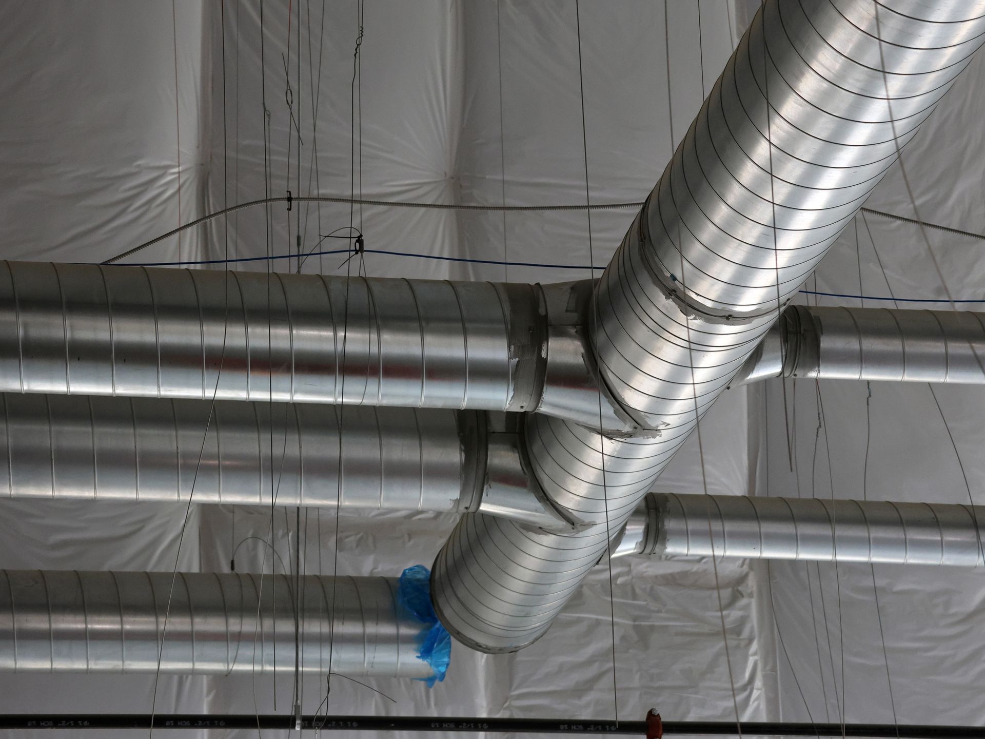 A bunch of metal pipes are hanging from the ceiling of a building.
