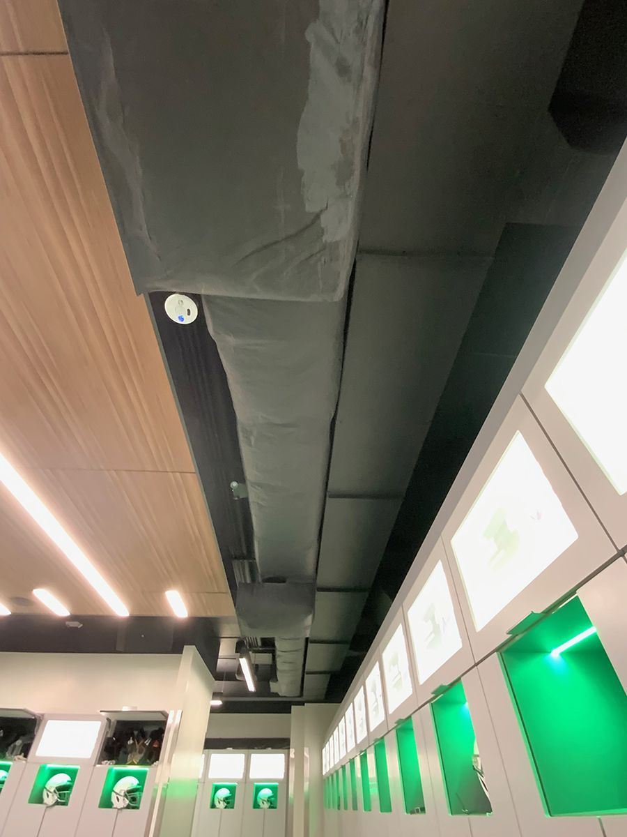 A room with a lot of green lockers and a ceiling