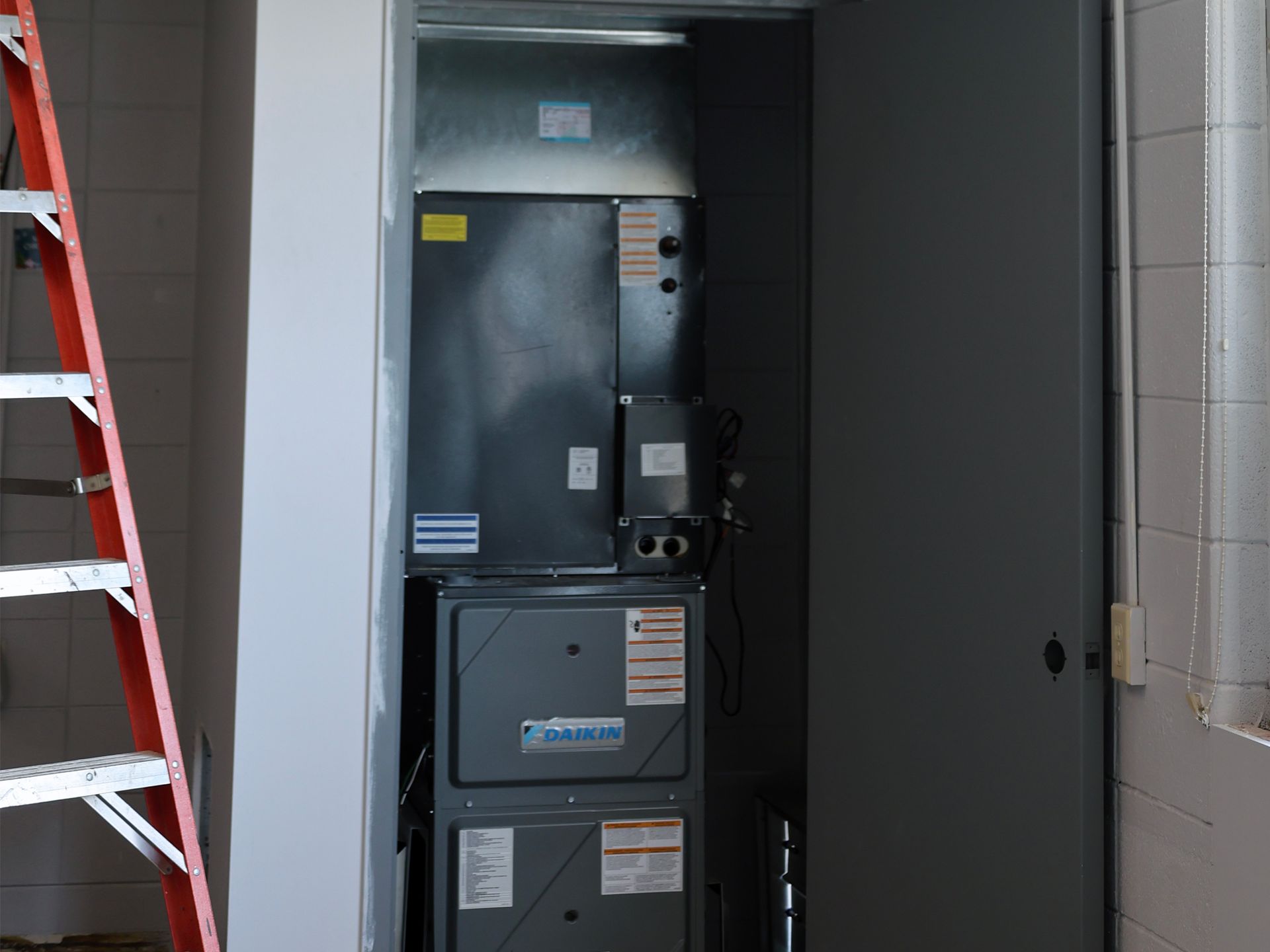 A ladder is leaning against a wall next to an air conditioner