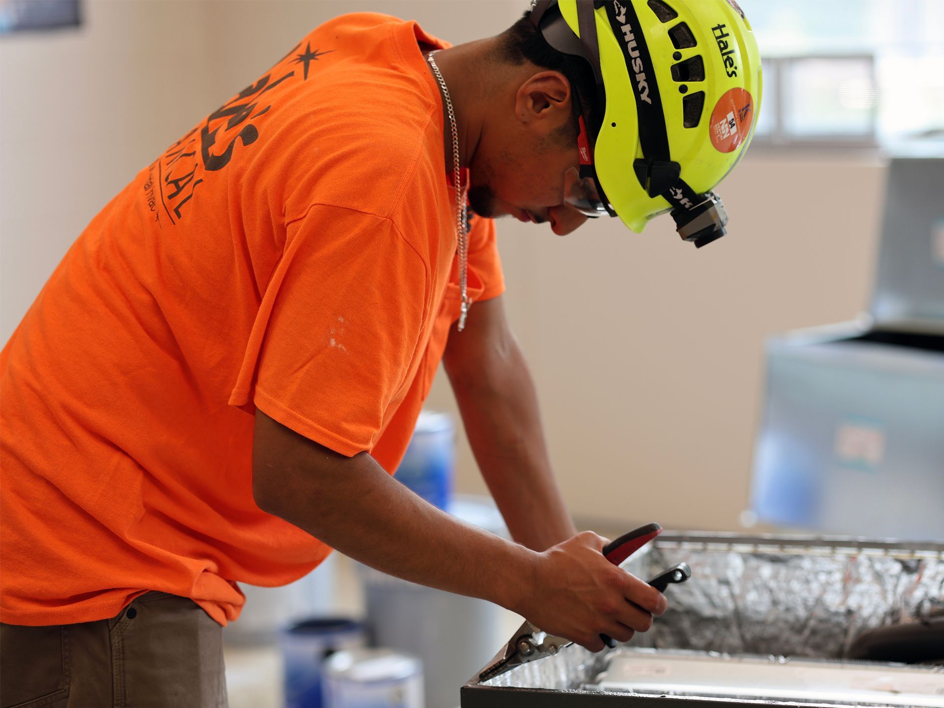 A man wearing an orange shirt and a yellow helmet with the word petzl on it