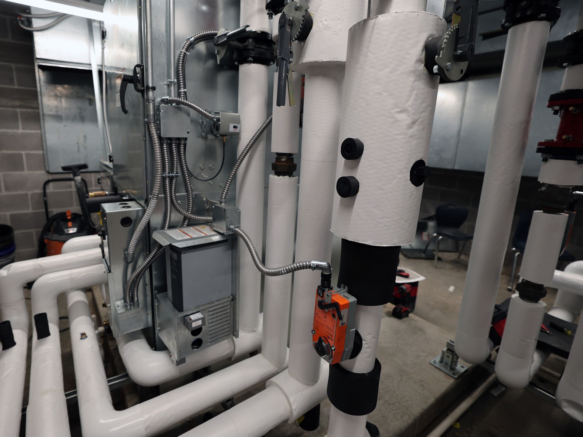 White pipes and equipment in an industrial setting with insulation and control panels.
