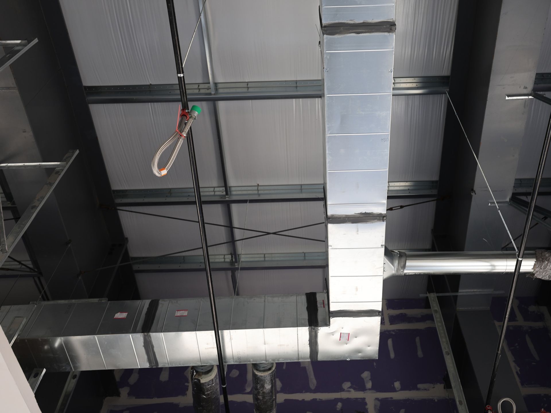 Metal HVAC ductwork and ceiling support framing in a commercial building under construction.