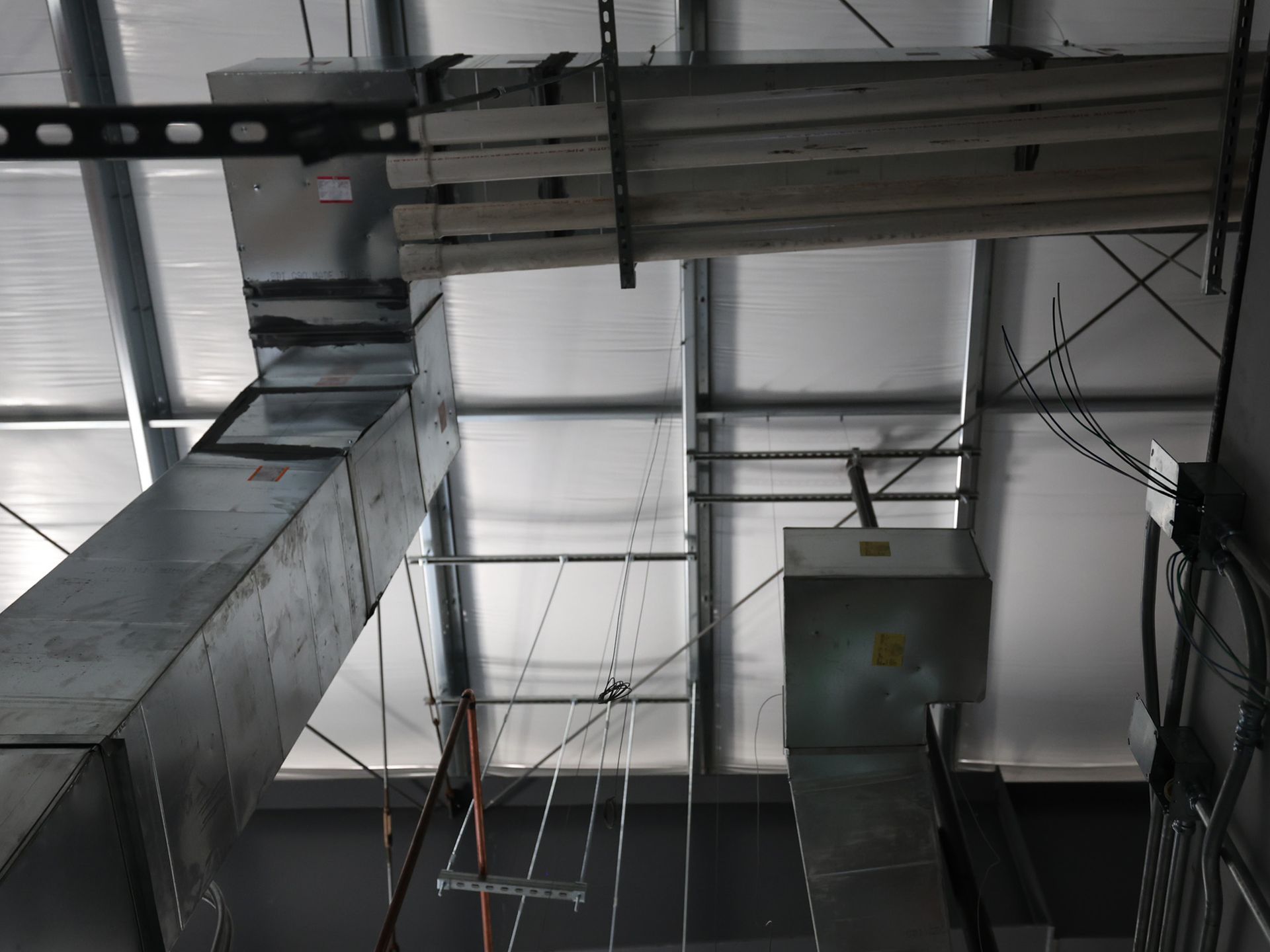 Metal ductwork in an industrial setting against a white ceiling.